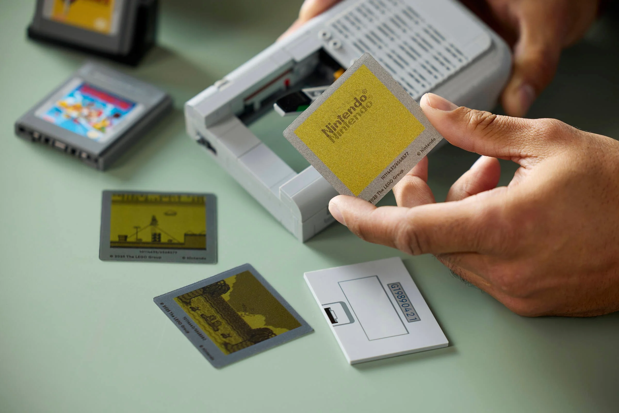 Prim plan cu cartușe LEGO Game Boy, inclusiv cel Nintendo, prezentat în mână.