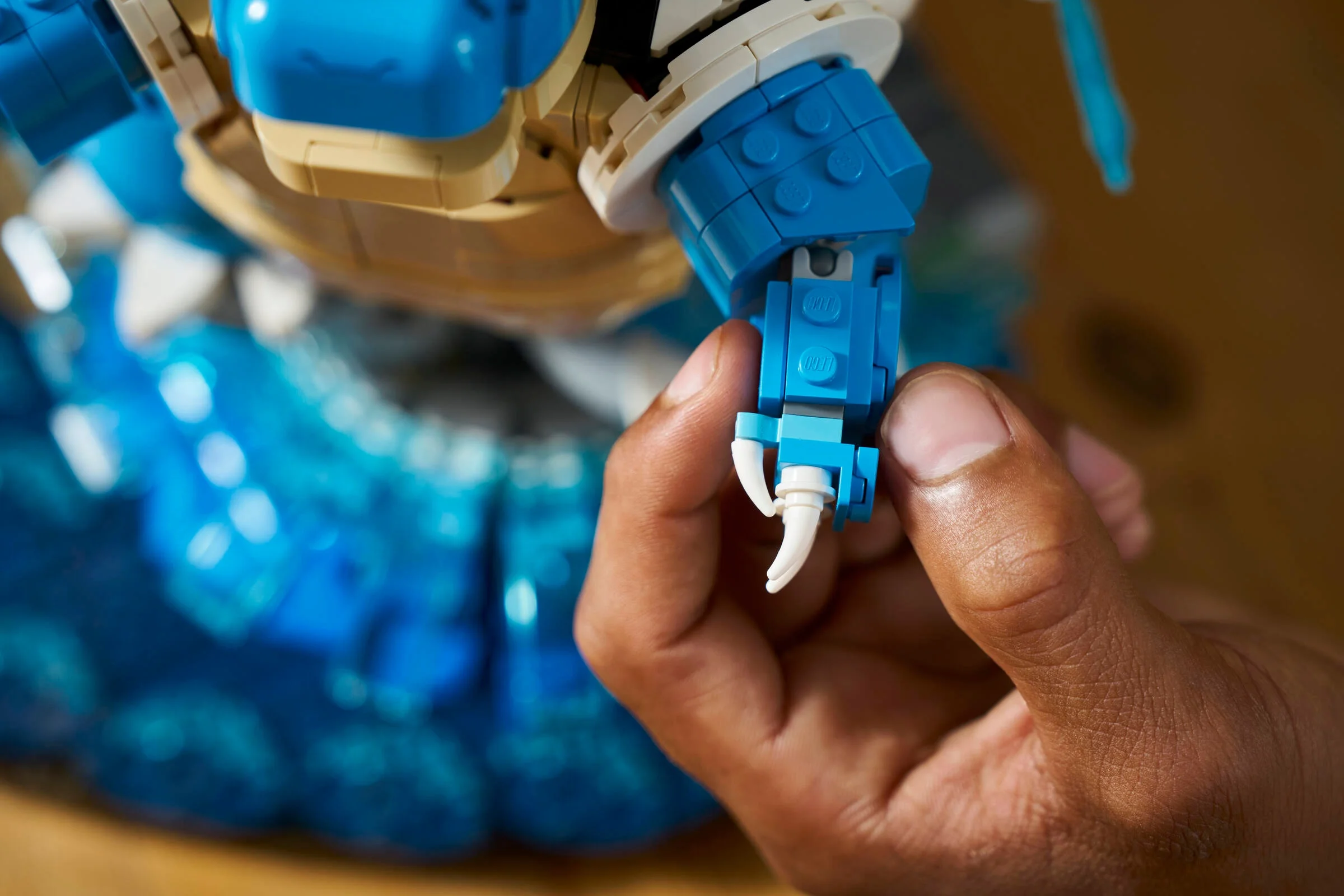 Prim-plan cu mâna unui adult asamblând detaliile LEGO ale lui Blastoise.