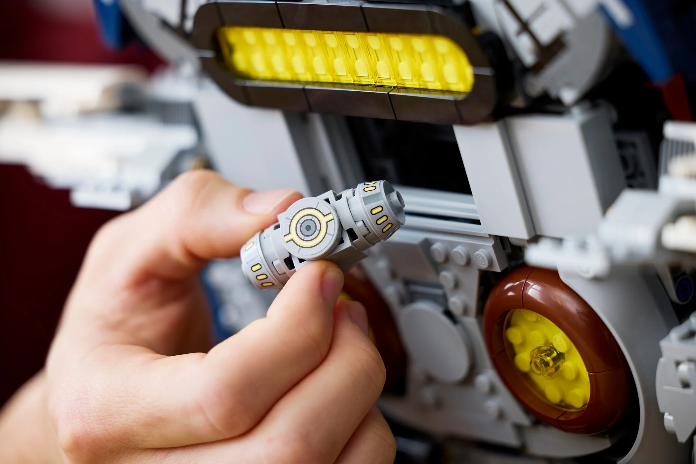 Mână asamblând detaliu mic al navetei spațiale LEGO Jango Fett, evidențiind construcția.