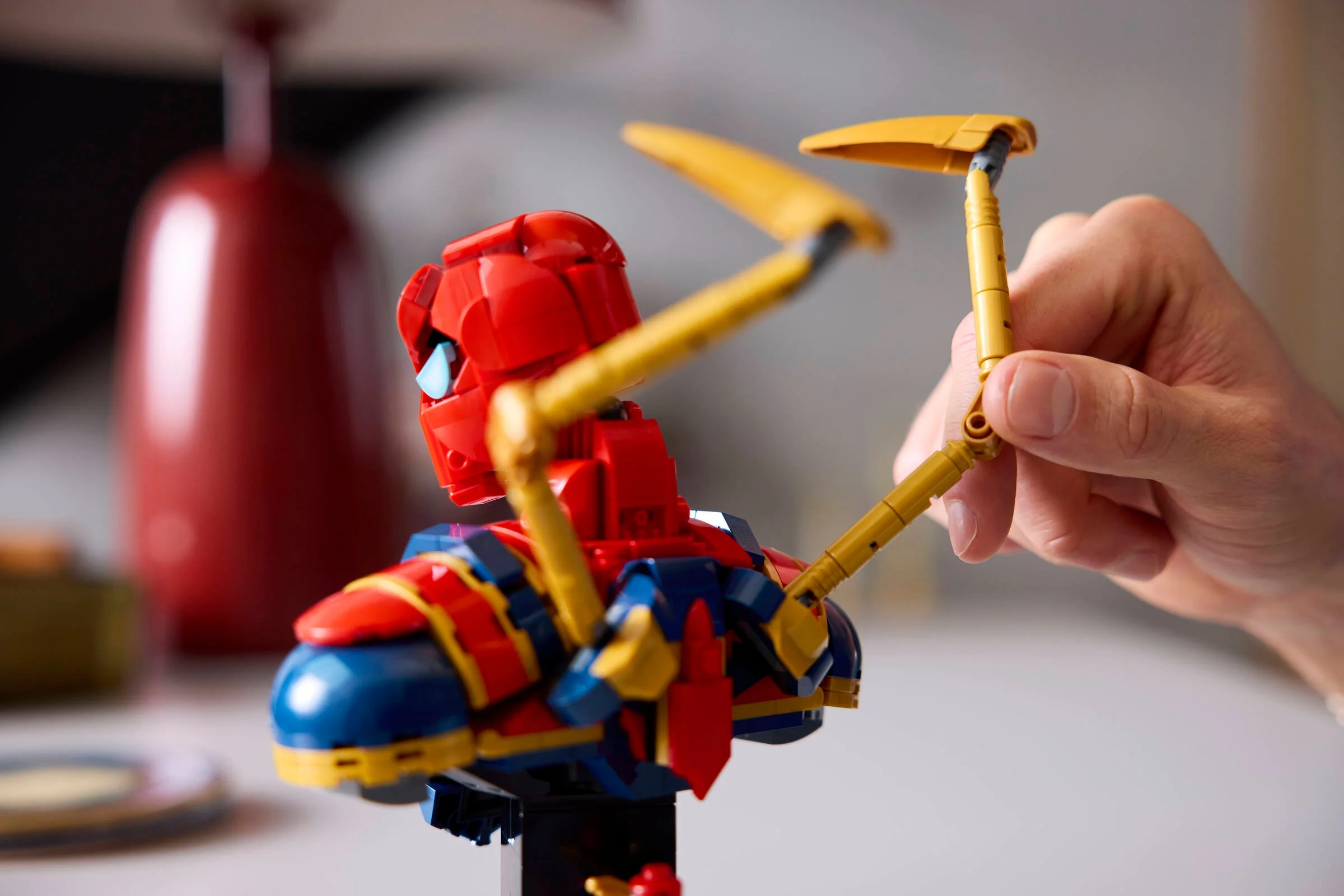 Prim plan cu bustul Iron Spider-Man, accent pe brațele mecanice aurii.