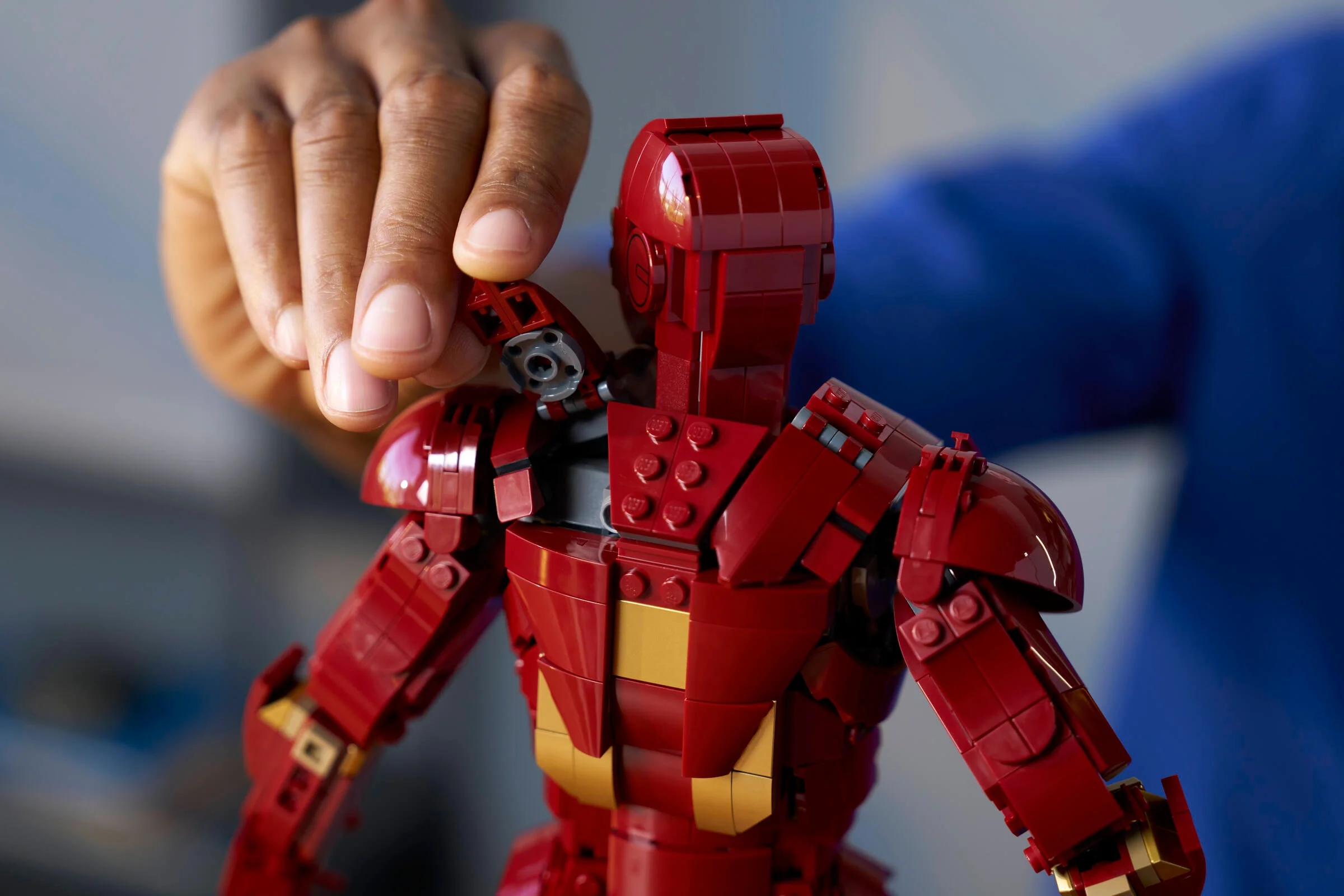 Mâna ajustează brațul figurinei Iron Man Mark 3. Detaliu al construcției și articulațiilor.