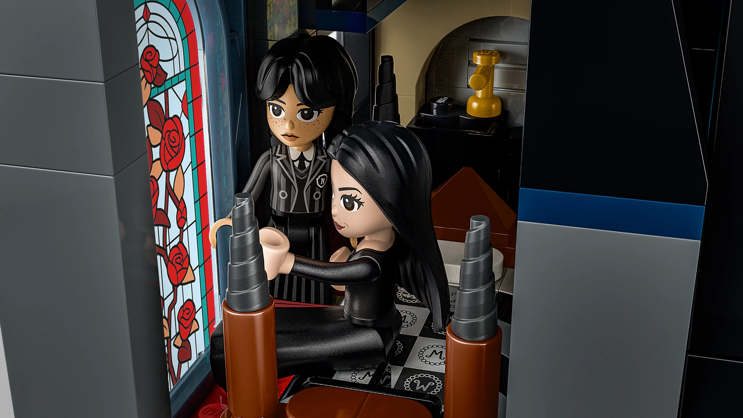 Detaliu cu figurinele Morticia și Wednesday în căsuța Addams Family. Interior cu vitraliu și mobilier.