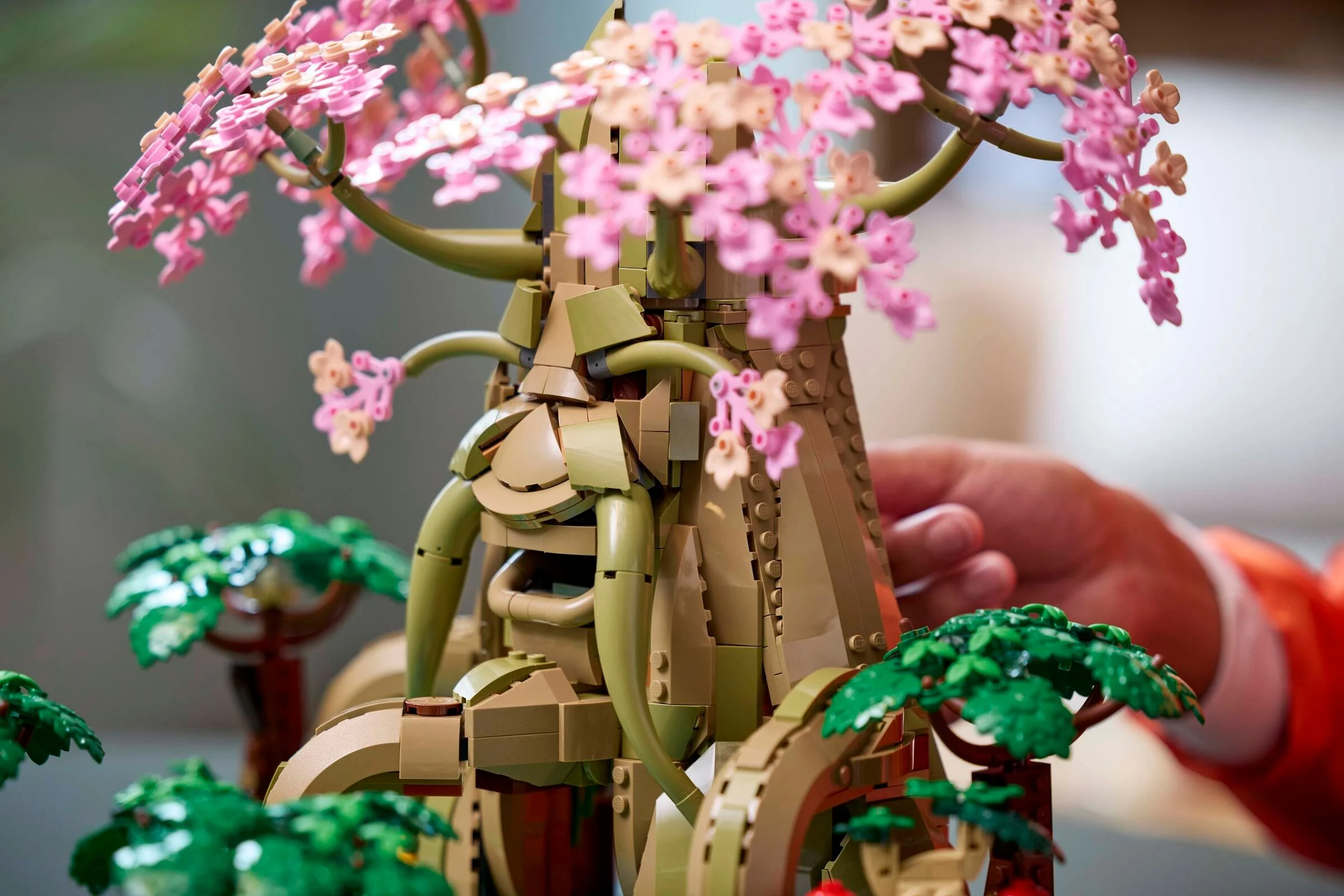 Prim-plan al modelului LEGO Great Deku Tree cu flori roz și elemente de peisaj.