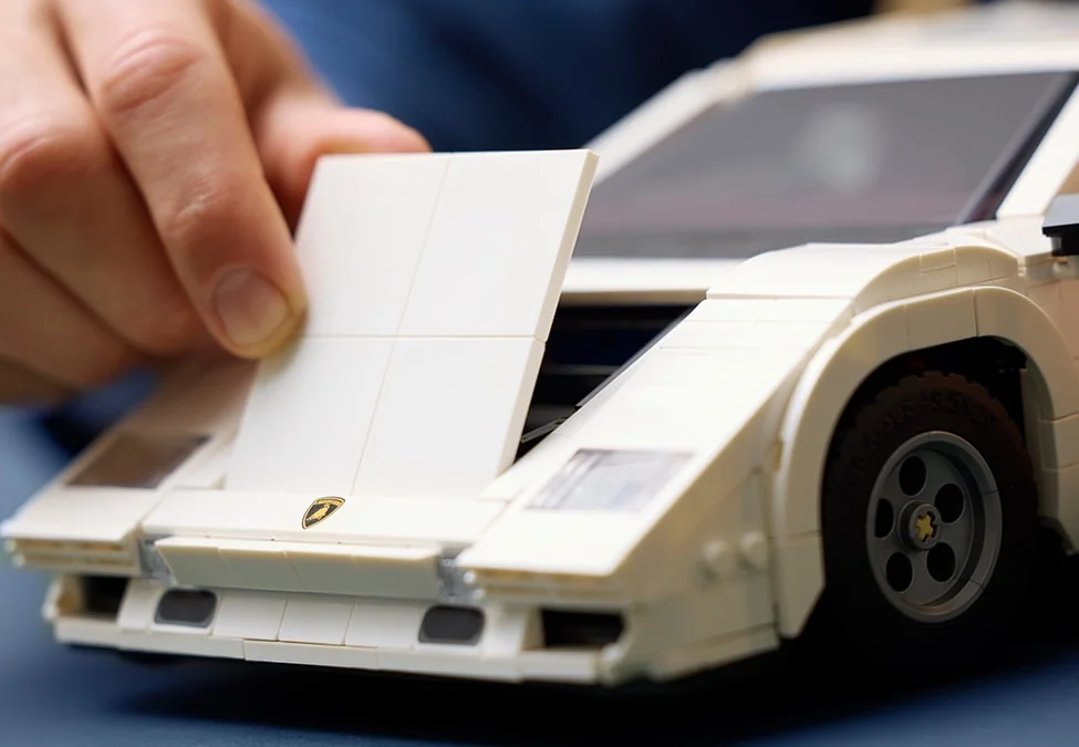 Capota frontală a mașinii Lamborghini Countach albă este deschisă.
