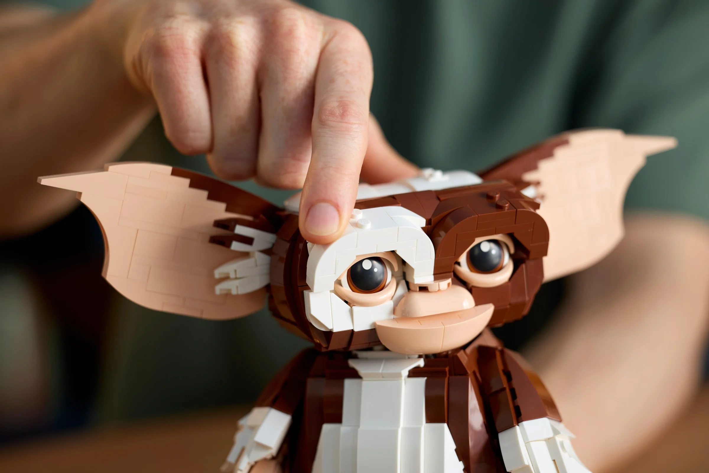 Gizmo LEGO, prezentat cu o mână ajustând o parte a feței. Detalii realiste și construcție complexă.