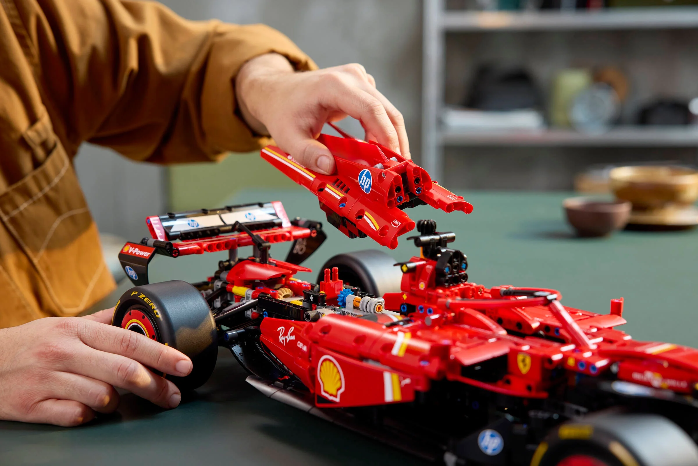 Mâini asamblând detaliile monopostului Ferrari SF-24 F1. Elemente tehnice vizibile.