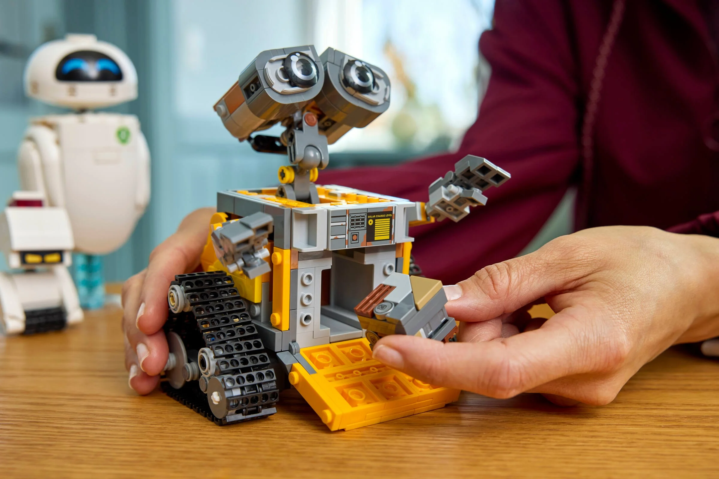 WALL-E LEGO interacționând cu mâinile, detaliu al funcționalității. EVE e vizibilă în fundal.