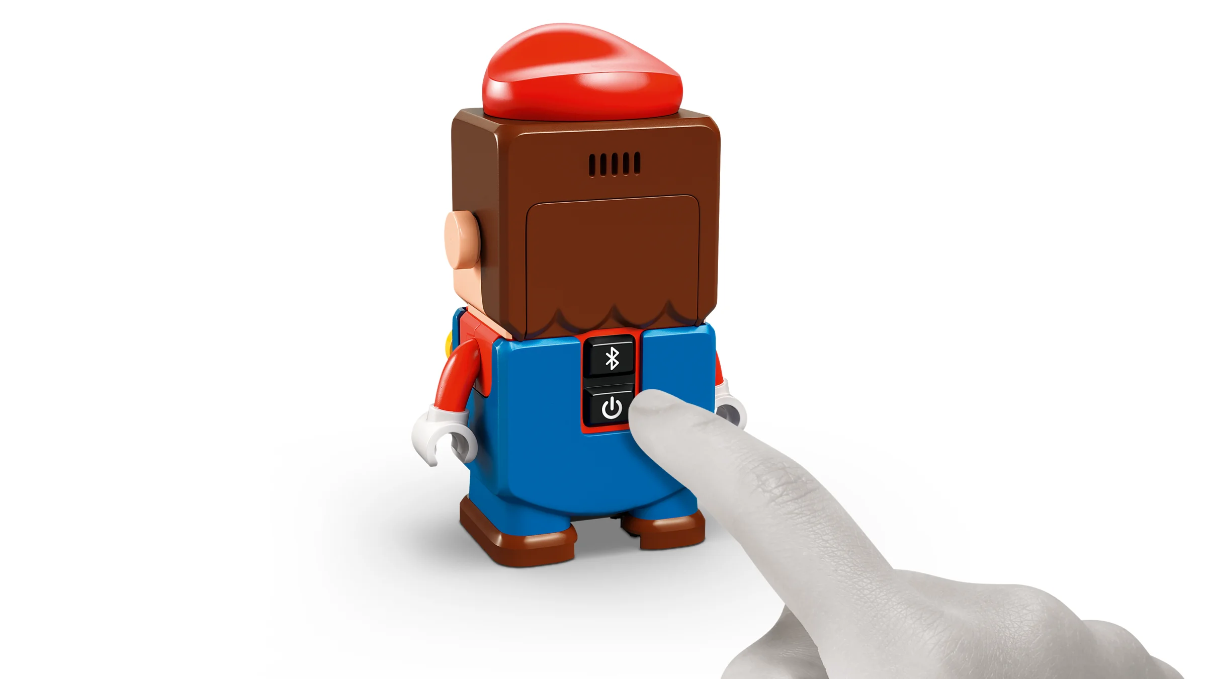 Mario interactiv LEGO este pornit, cu un deget apăsând butonul de pornire.