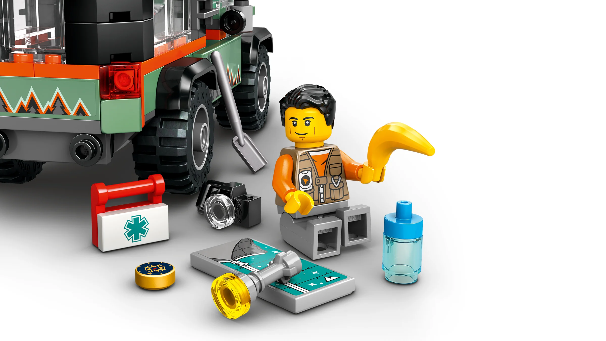 Minifigurină și accesorii lângă o parte din camion. Accesorii: lopată, trusă medicală, busolă, hartă, sticlă apă, cameră foto.