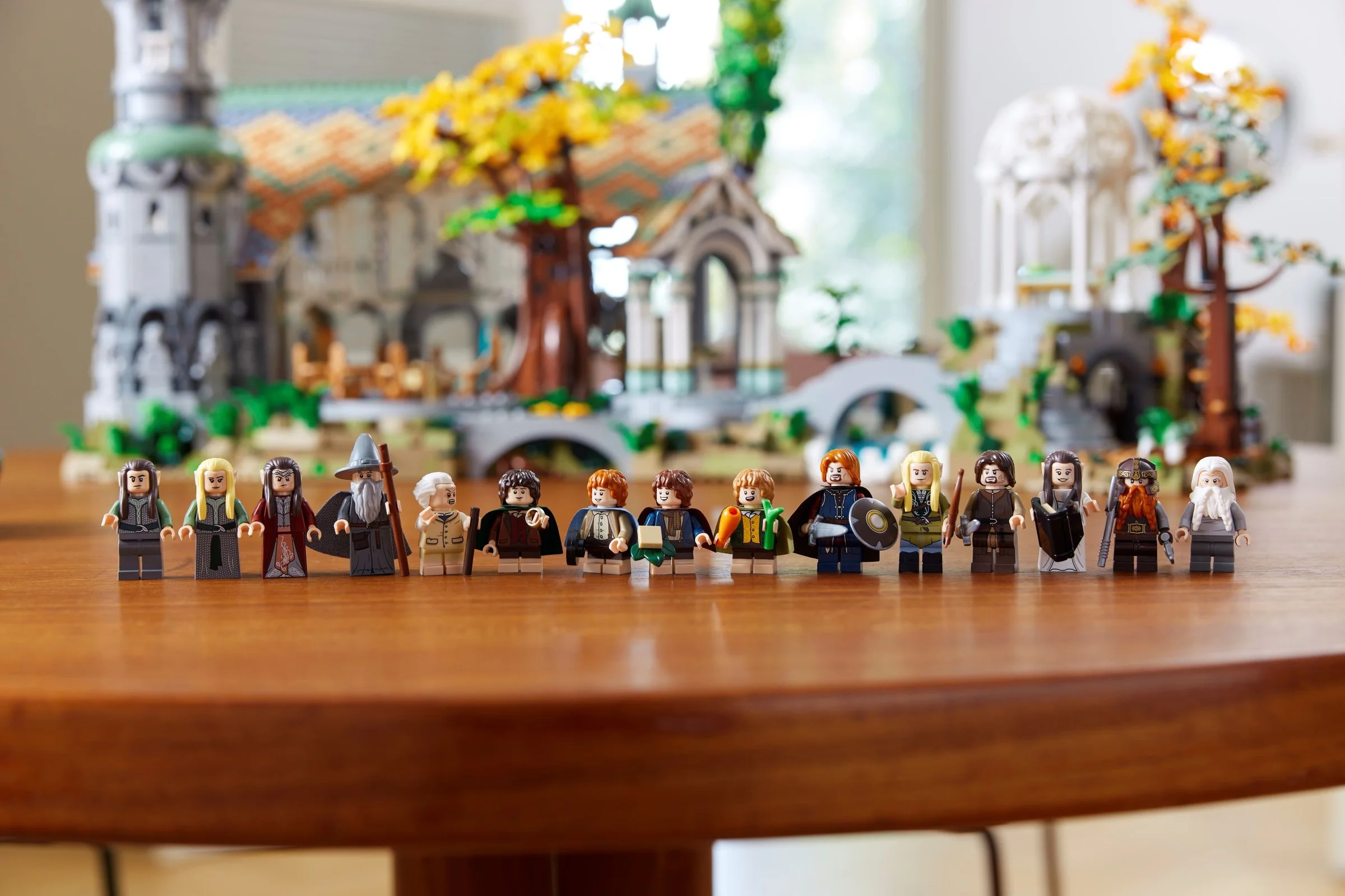 Imagine cu toate minifigurinele LEGO Rivendell, aliniate în fața modelului complet. Personaje detaliate, scenă pitorească.