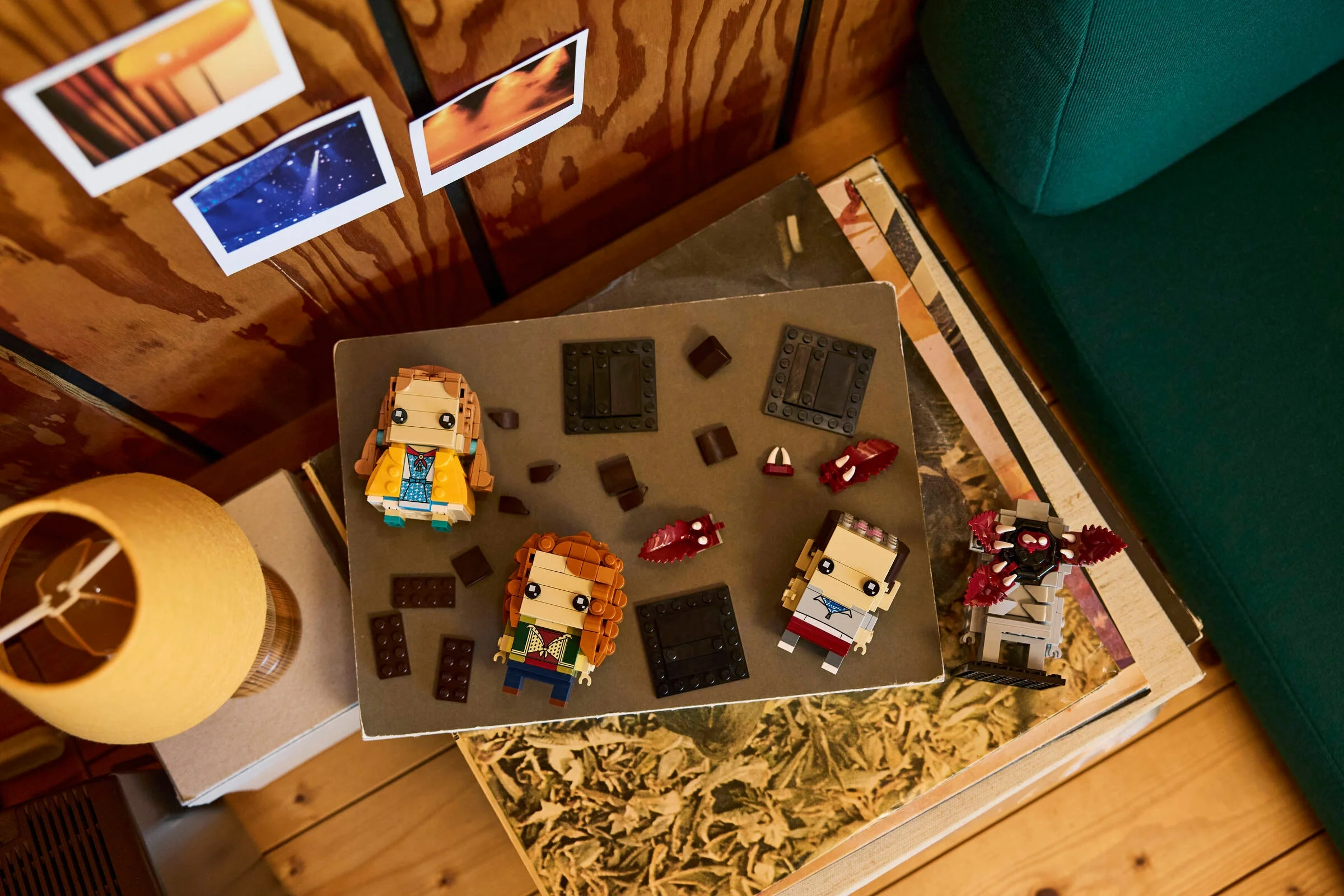Imagine cu figurinele BrickHeadz Eleven, Max, Demogorgon și Holly (40879) pe o măsuță, lângă o lampă.