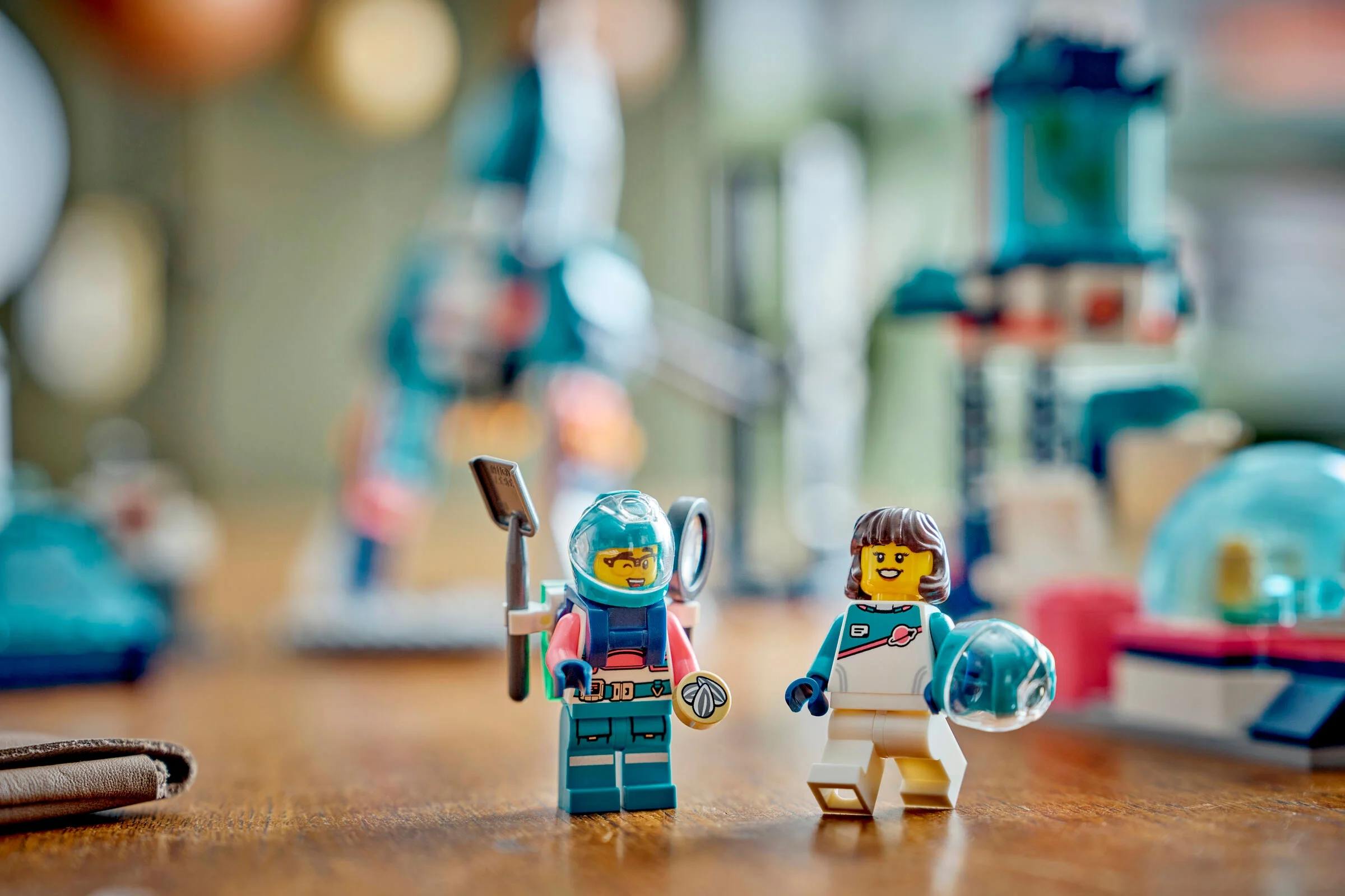 Prim plan cu două minifigurine astronaut LEGO, în fundal o bază lunară neclară.