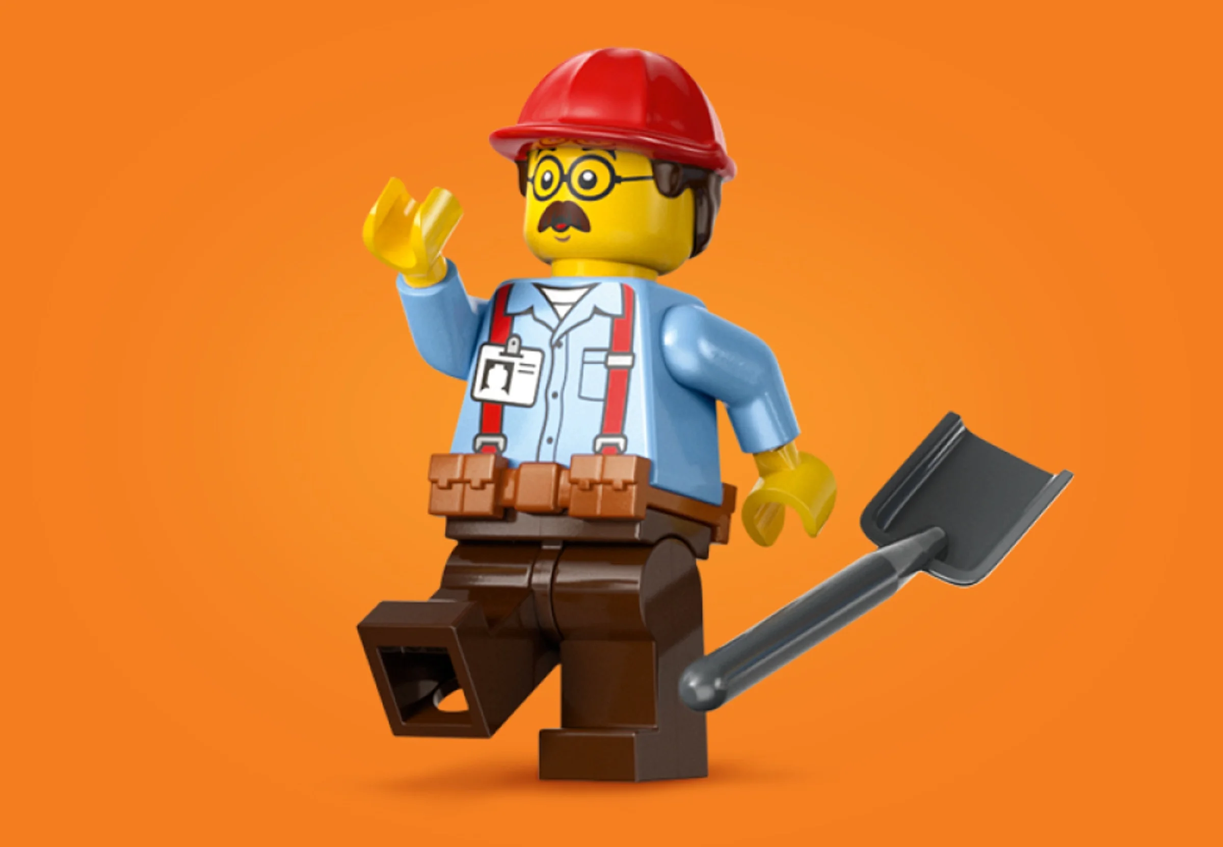 Minifigurină LEGO constructor cu cască roșie și lopată, fundal portocaliu.