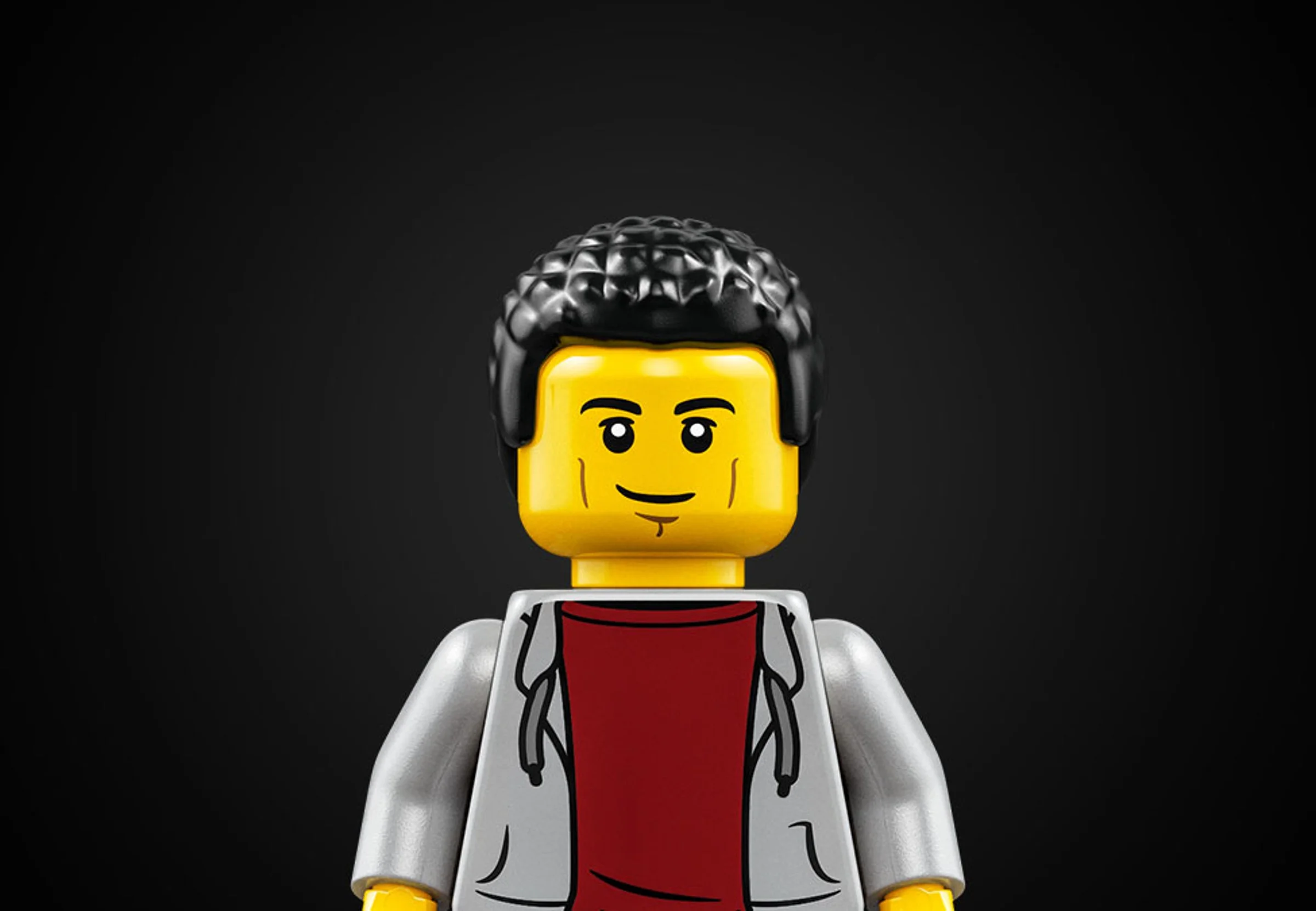 Prim-plan cu minifigurina LEGO cu păr negru și hanorac gri. Detaliu atrăgător.