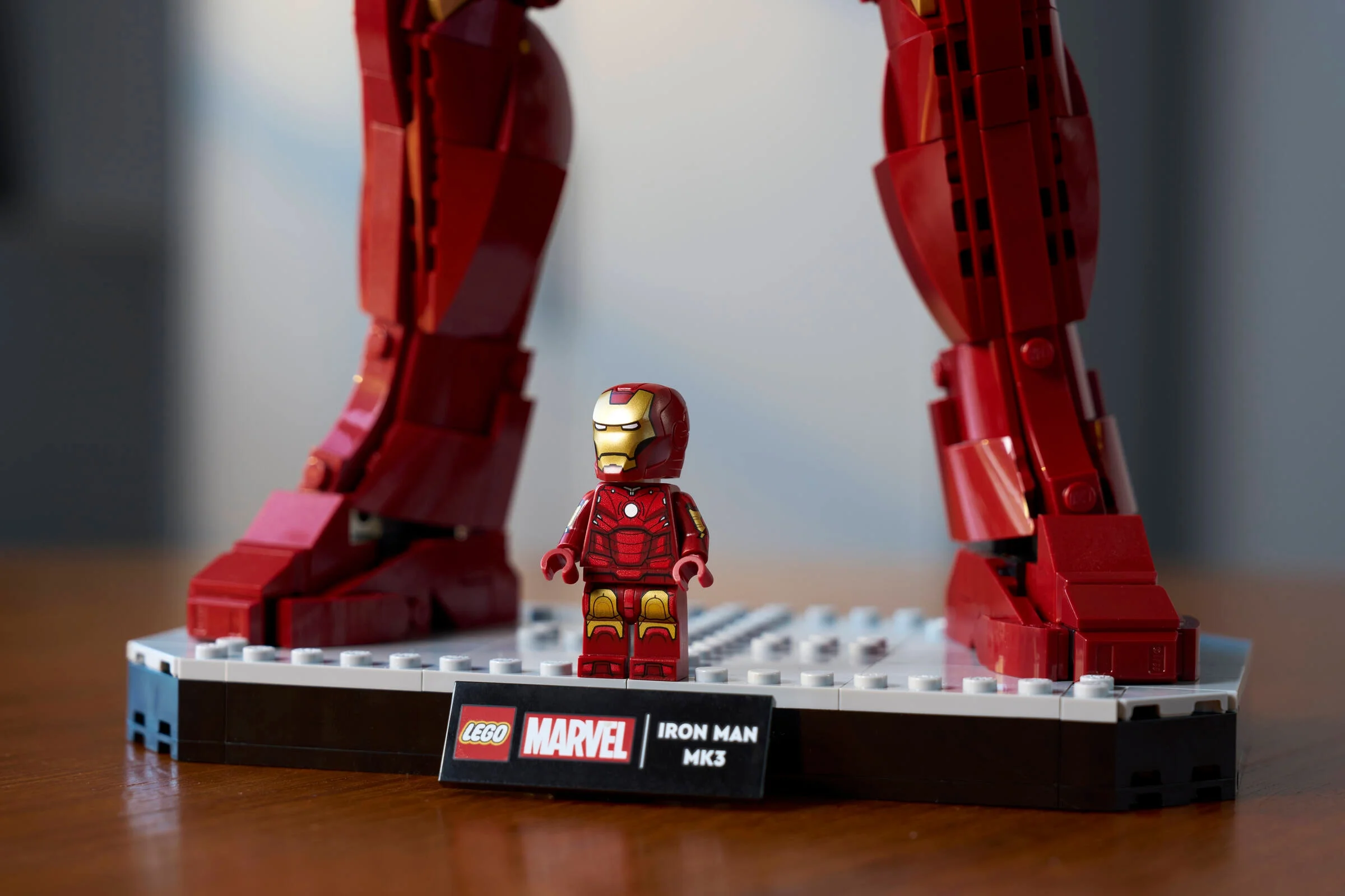 Prim-plan cu minifigurina Iron Man Mark 3 lângă picioarele figurinei construibile.