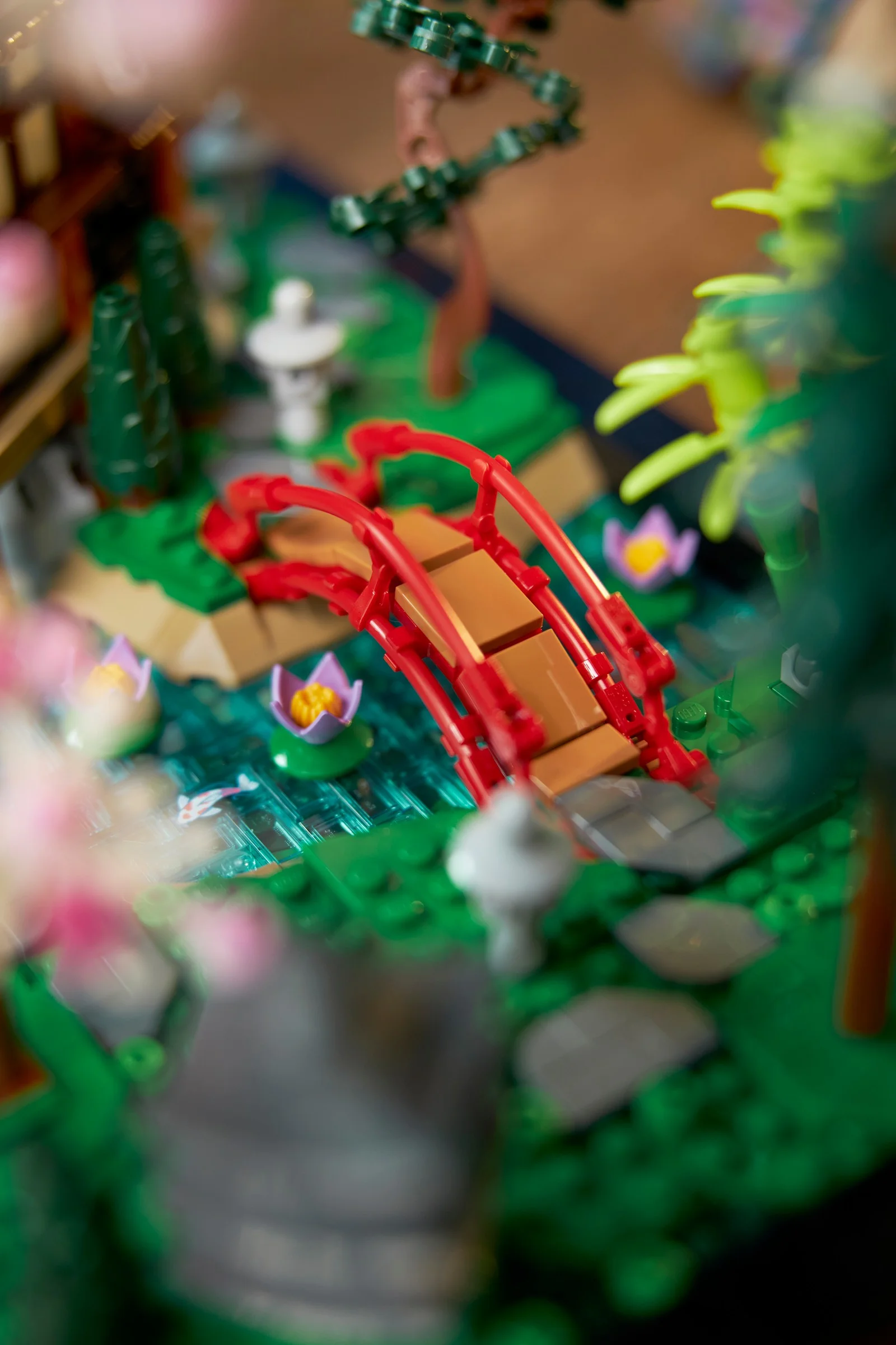 Detaliu al grădinii liniștite LEGO 10315, cu pod roșu, nuferi și pești koi în apă. Atmosferă relaxantă.