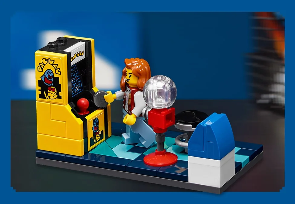 Mini-dioramă LEGO Pac-Man cu un mini-figură jucând la un arcade și alte elemente retro.