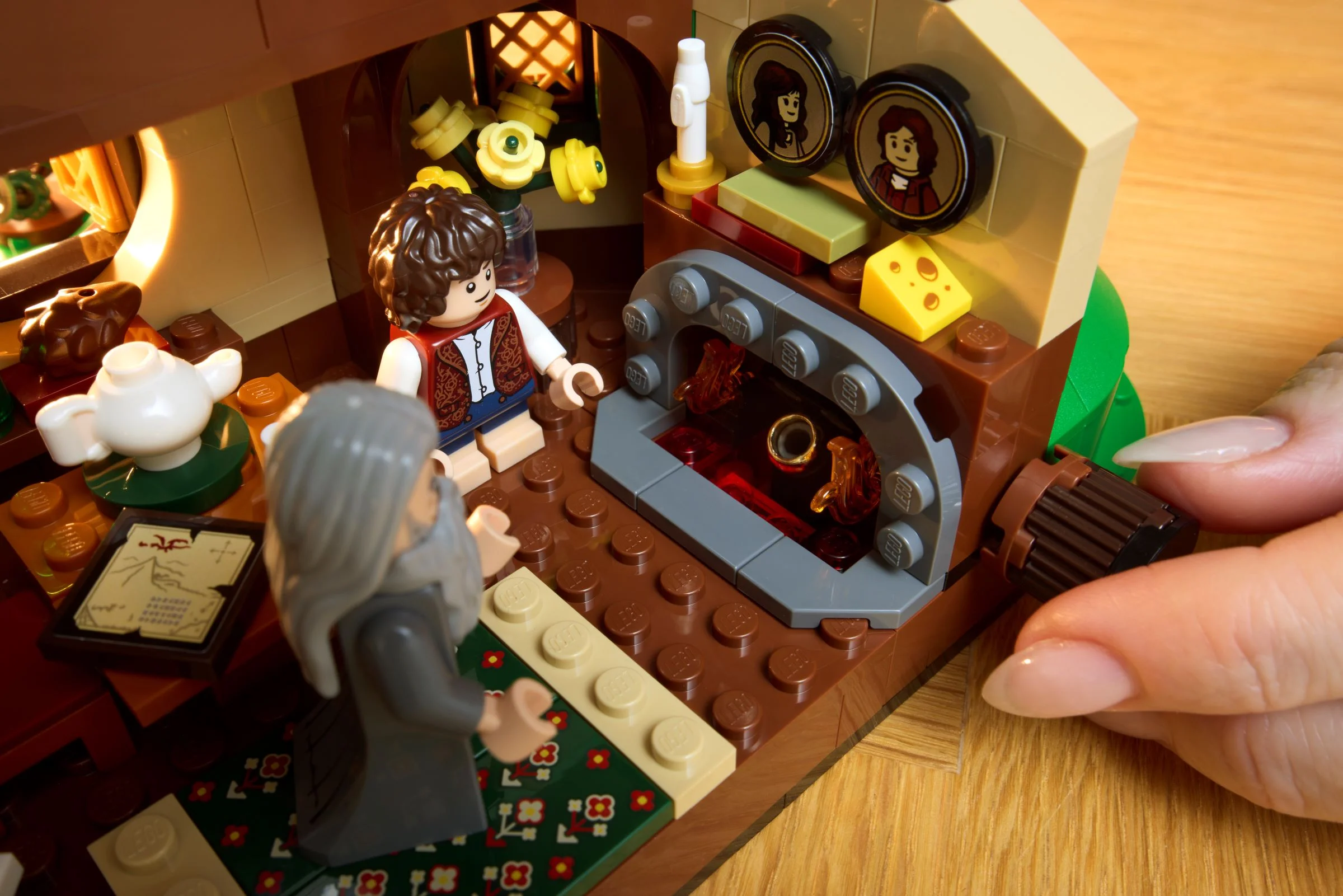 Interiorul căsuței Hobbiton cu minifigurinele Gandalf și Bilbo, aragazul și detalii din interior. Atmosferă primitoare.