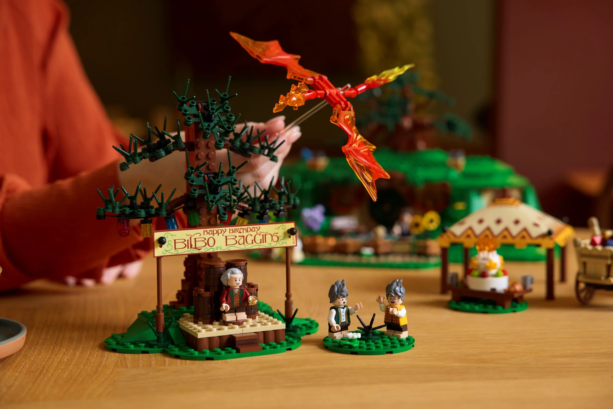 Imagine cu minifigurine din setul LEGO Hobbit: Bilbo, hobbiți, dragon, scenă aniversară.