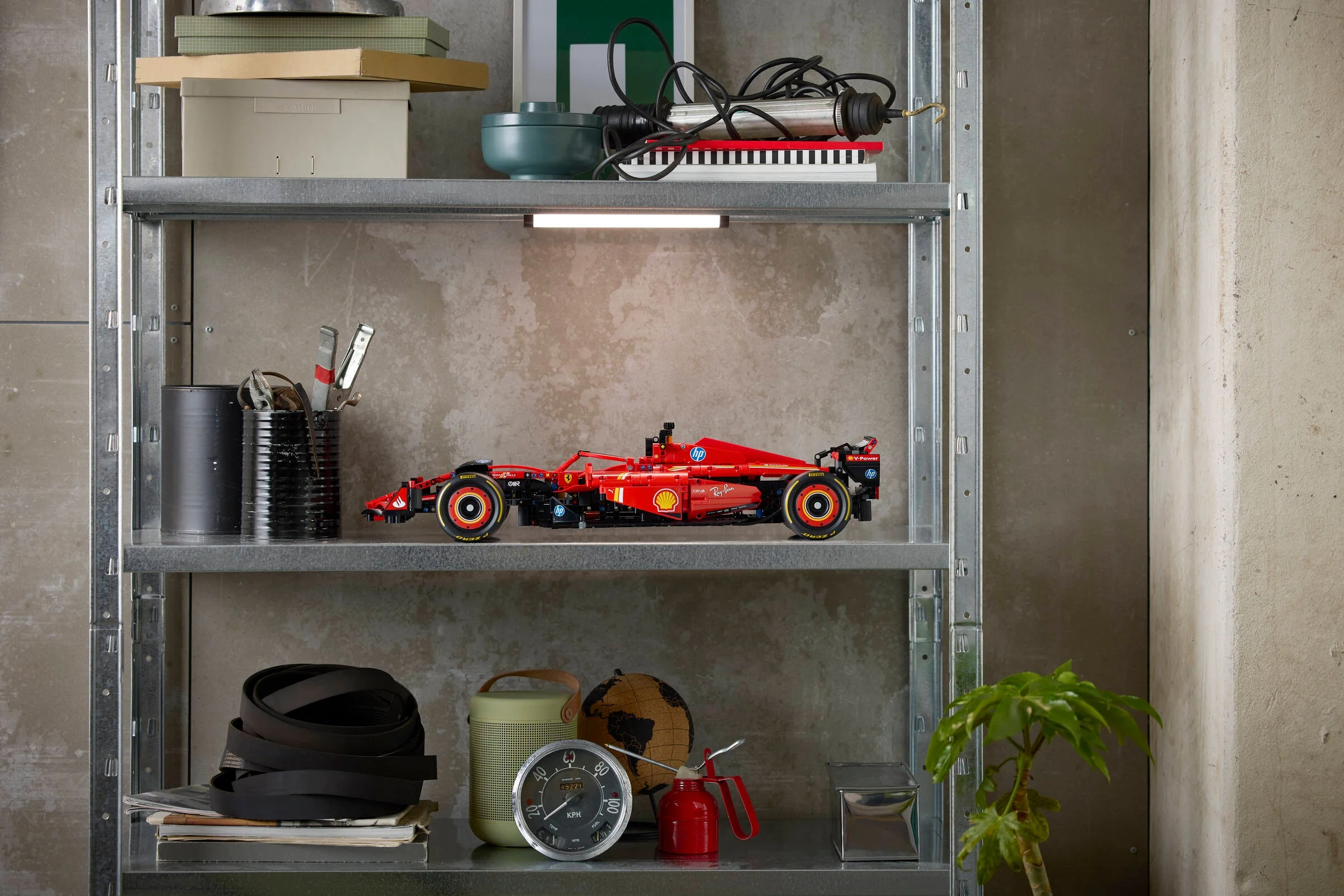Mașina Ferrari SF-24 F1 LEGO Technic expusă pe un raft metalic, într-un context creativ.