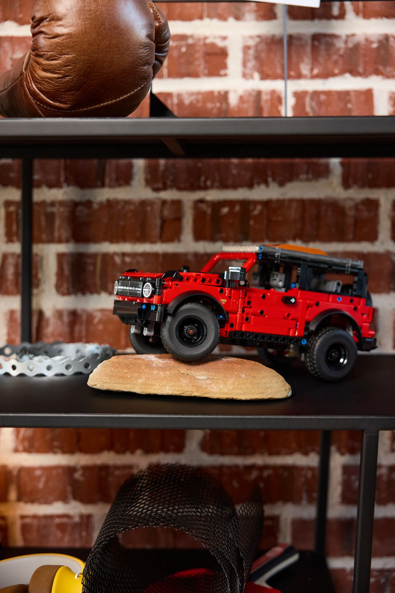 Modelul Ford Bronco SUV (42213) pe un raft, lângă alte obiecte. Detaliu frontal-lateral.