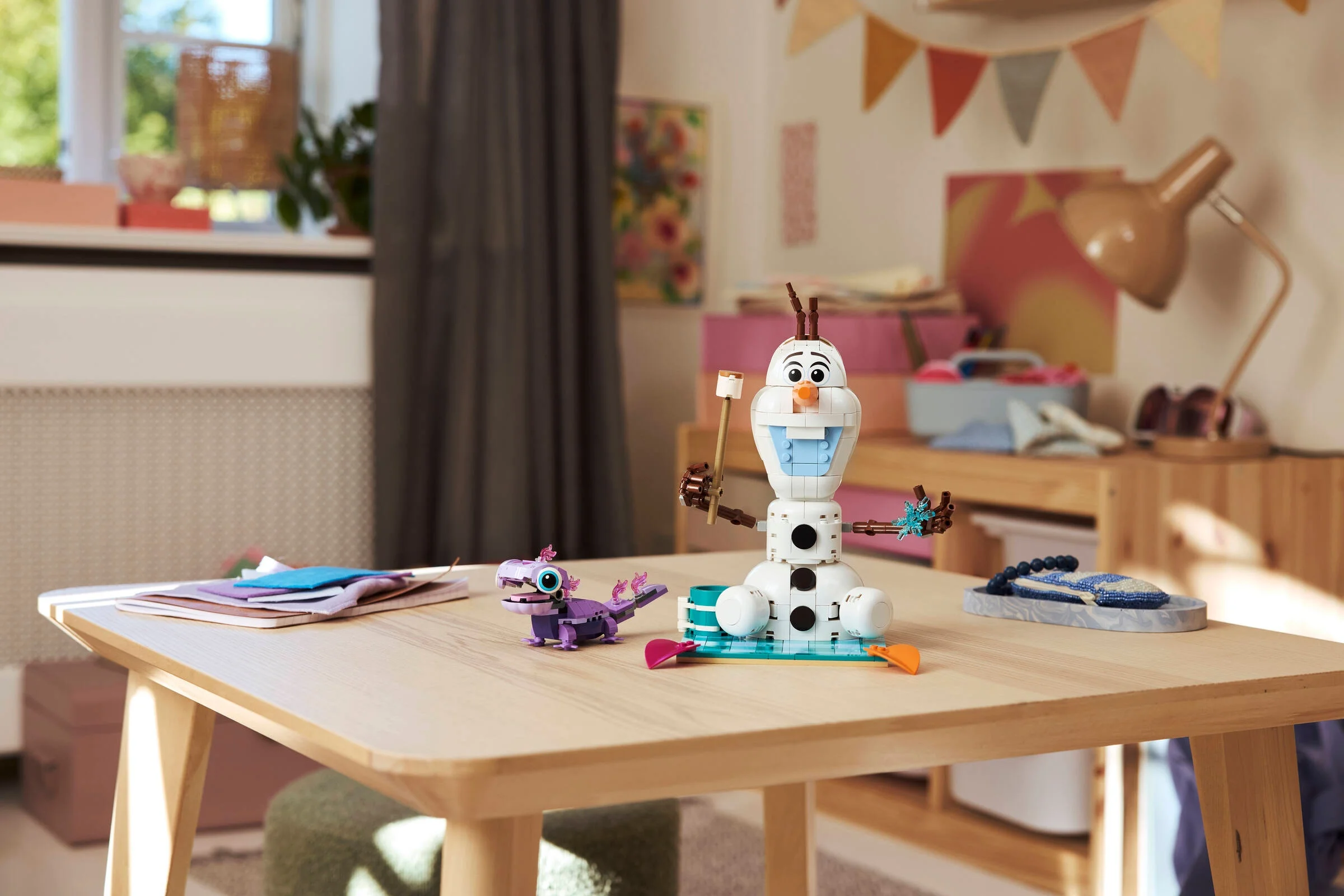 Olaf și Bruni LEGO la picnic pe o masă într-o cameră luminoasă.
