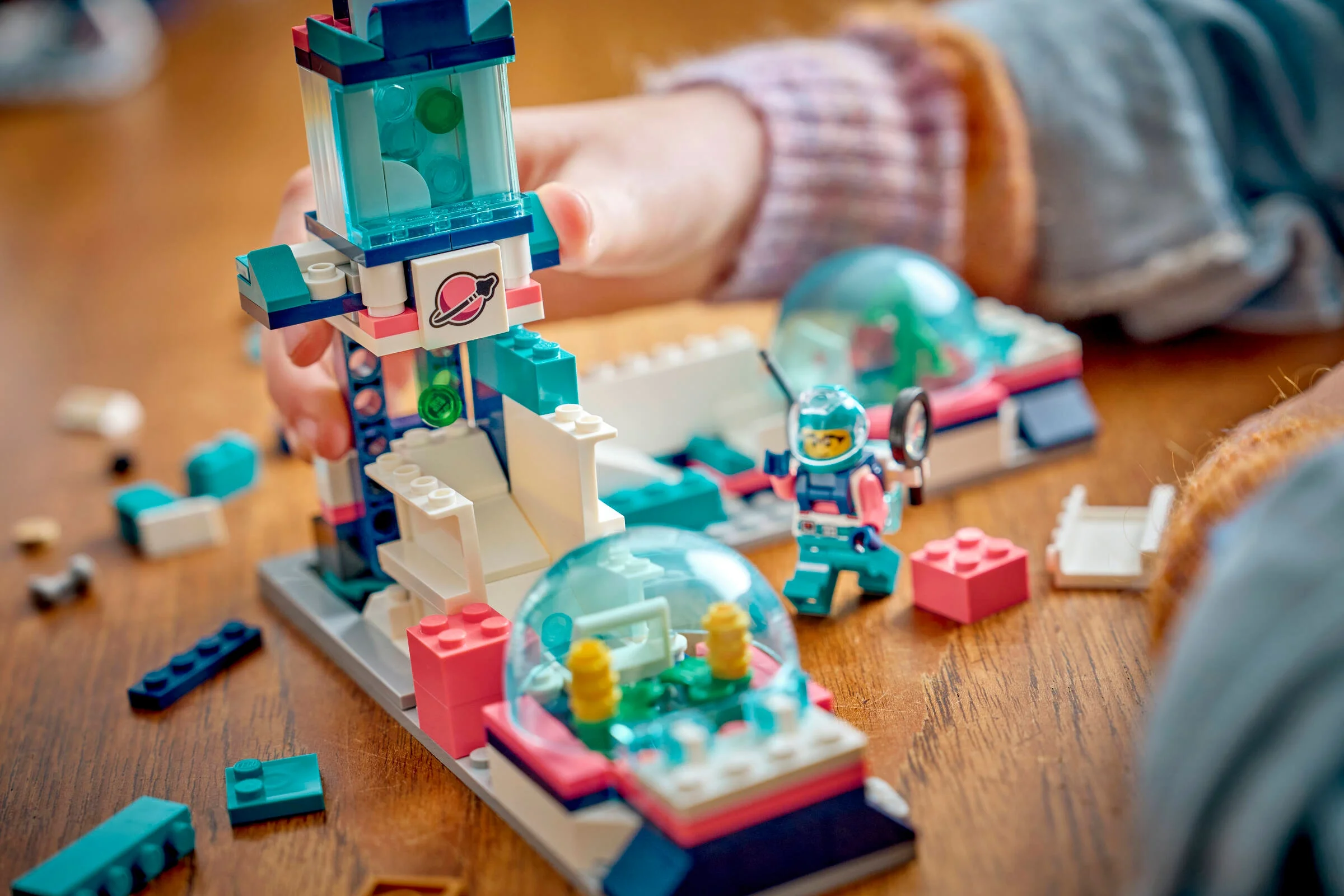 Copil construind un model LEGO cu tematică spațială, cu minifigurină astronaut.