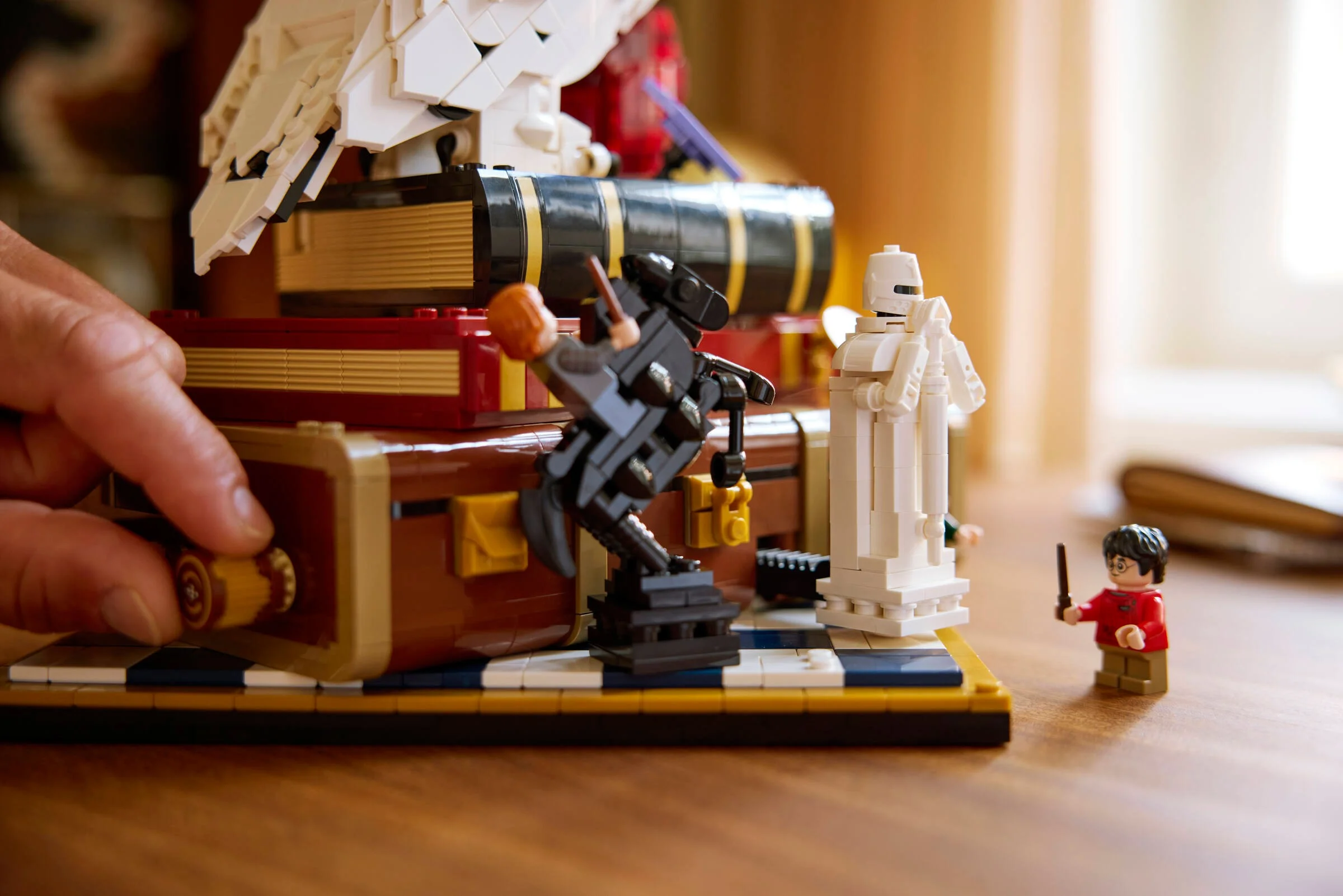 Scenă cu Harry Potter și figurinele din LEGO, cu o mână interacționând cu modelul.