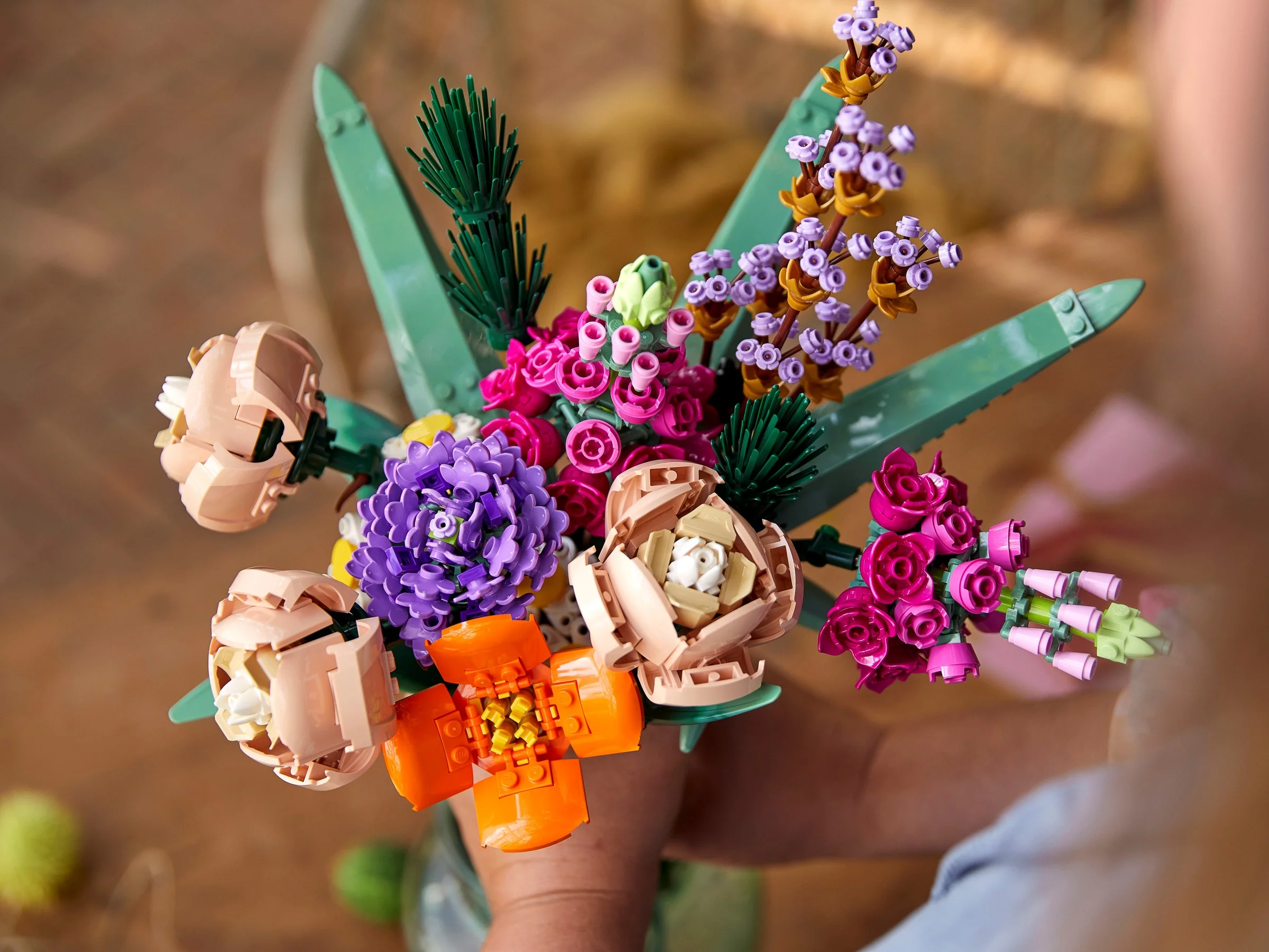 Buchet colorat de flori LEGO, 10280, ținut în mână. Detalii fine ale construcției.