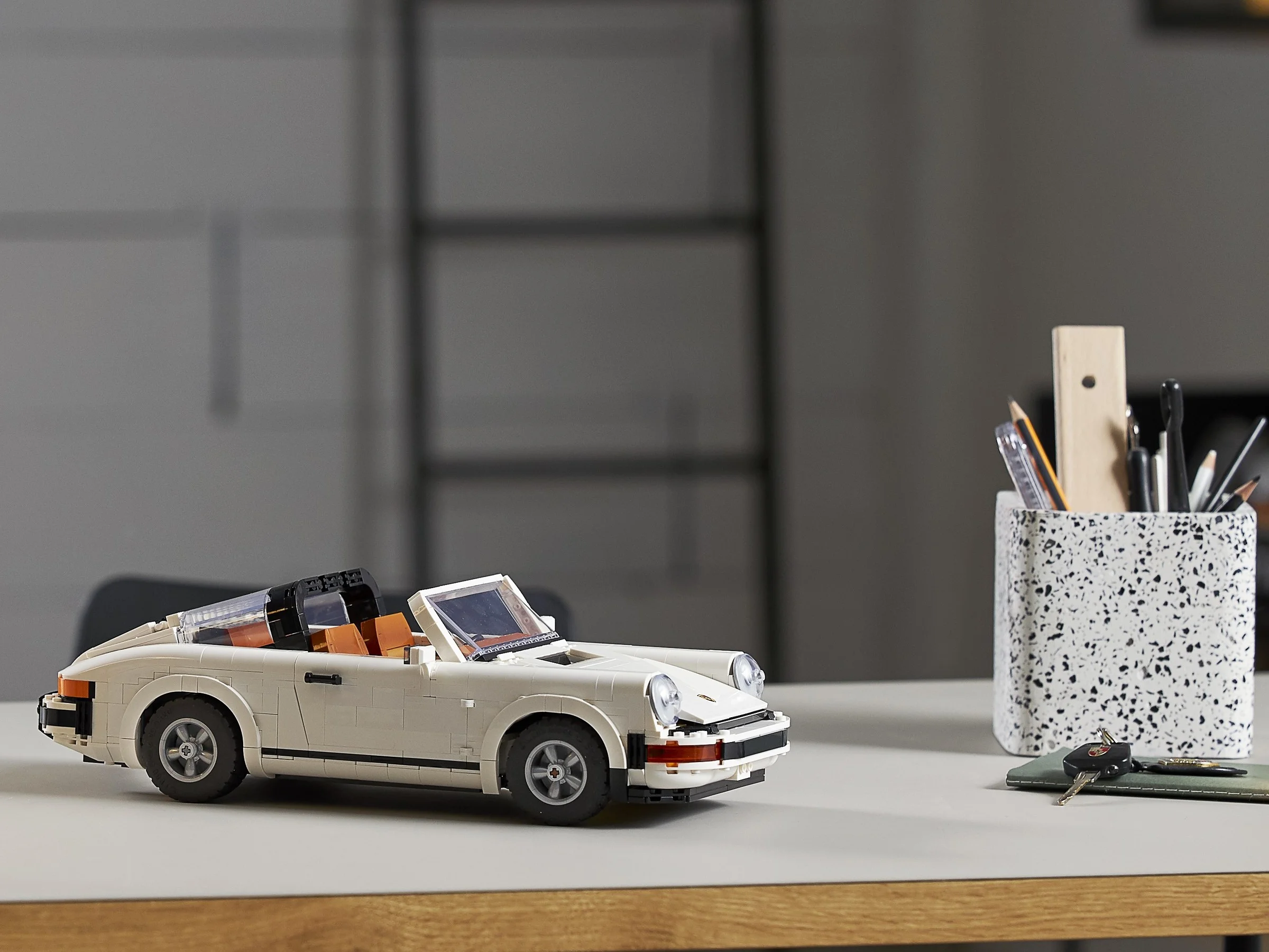 Porsche 911 decapotabilă, albă, expusă pe un birou. Detaliu elegant și rafinat.