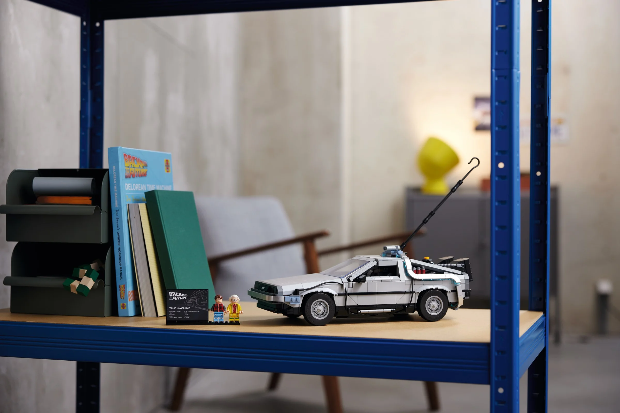 O imagine arată modelul LEGO DeLorean, alături de minifigurinele Marty și Doc, pe un raft.