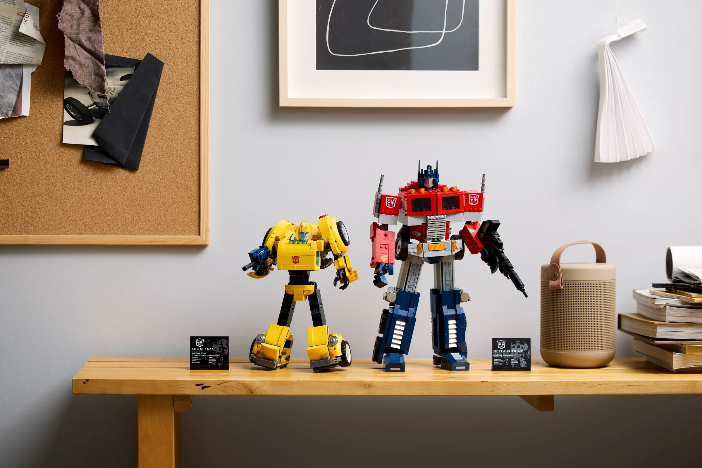 Imagine cu Bumblebee și Optimus Prime construiți din LEGO, pe o masă. Detaliu al seturilor.