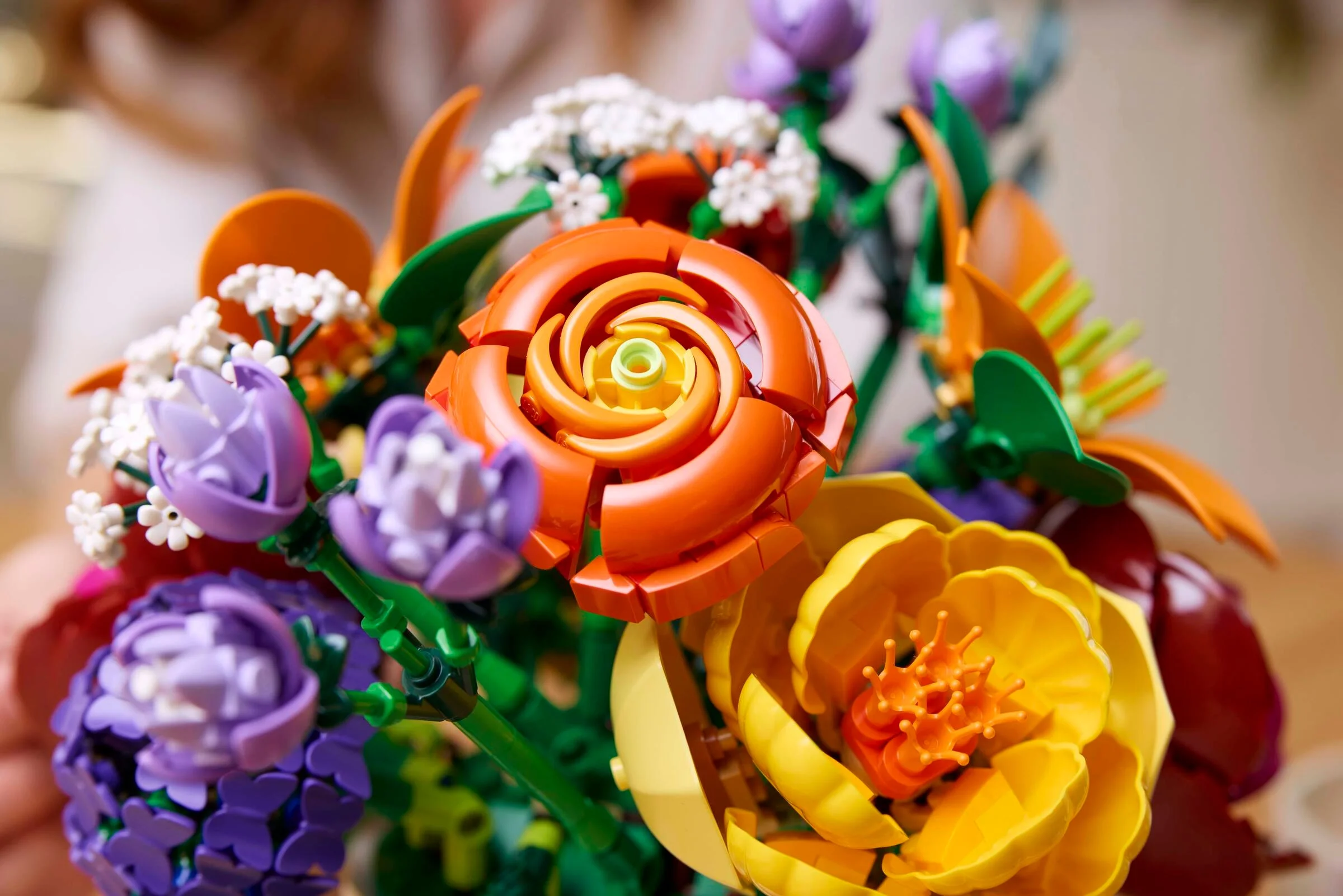 Aranjament floral LEGO cu trandafir oranj, lalele mov și alte flori. Detalii colorate.