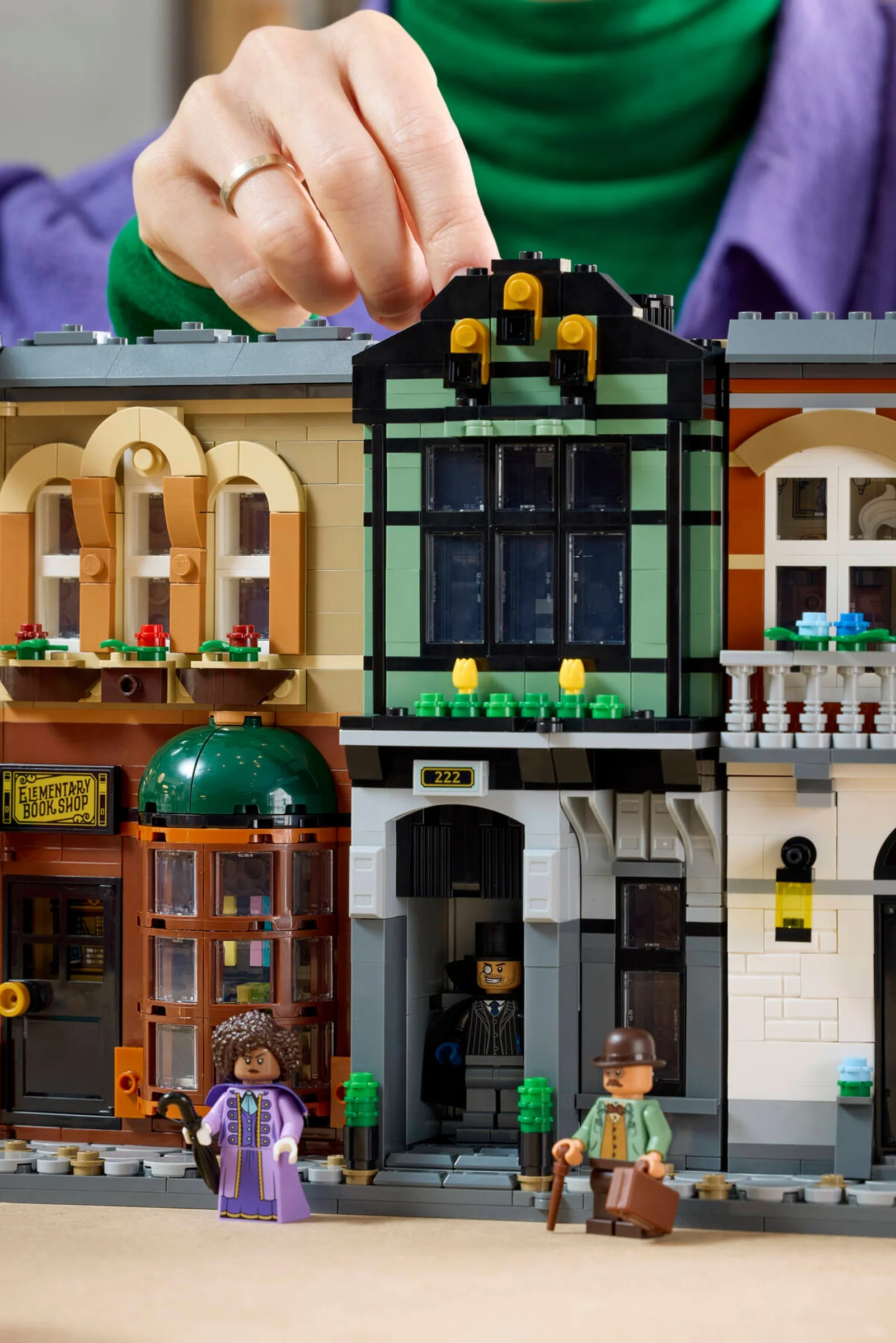O mână construiește ultimul etaj al clădirii cu numărul 222 din setul LEGO Sherlock Holmes.