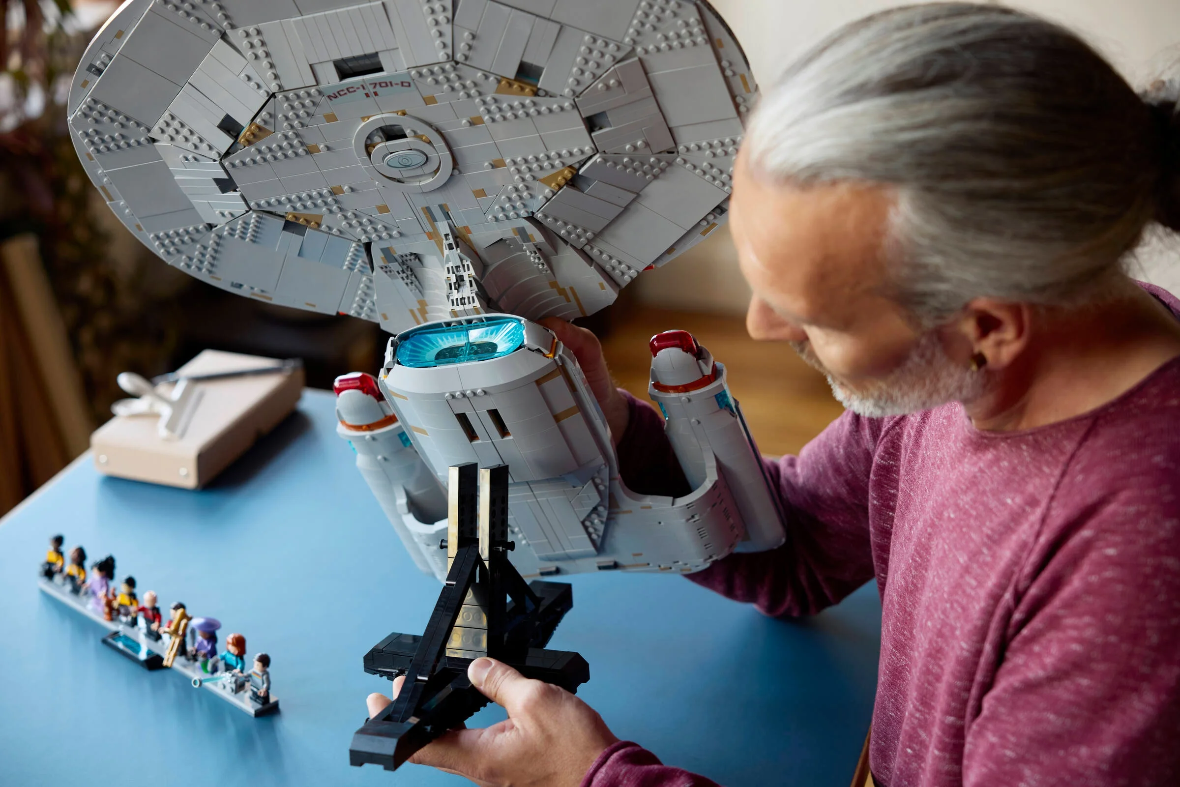 Un adult inspectează U.S.S. Enterprise NCC-1701-D LEGO, privind detaliile construcției.