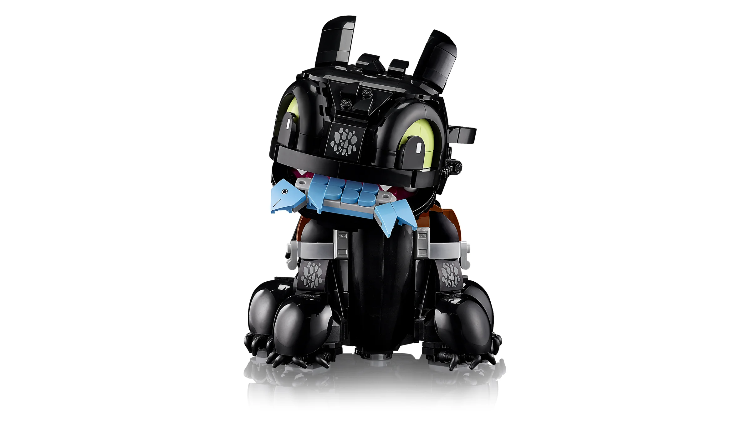 Toothless, dragonul simpatic, ține pește în gură. Detaliu drăguț al modelului LEGO.