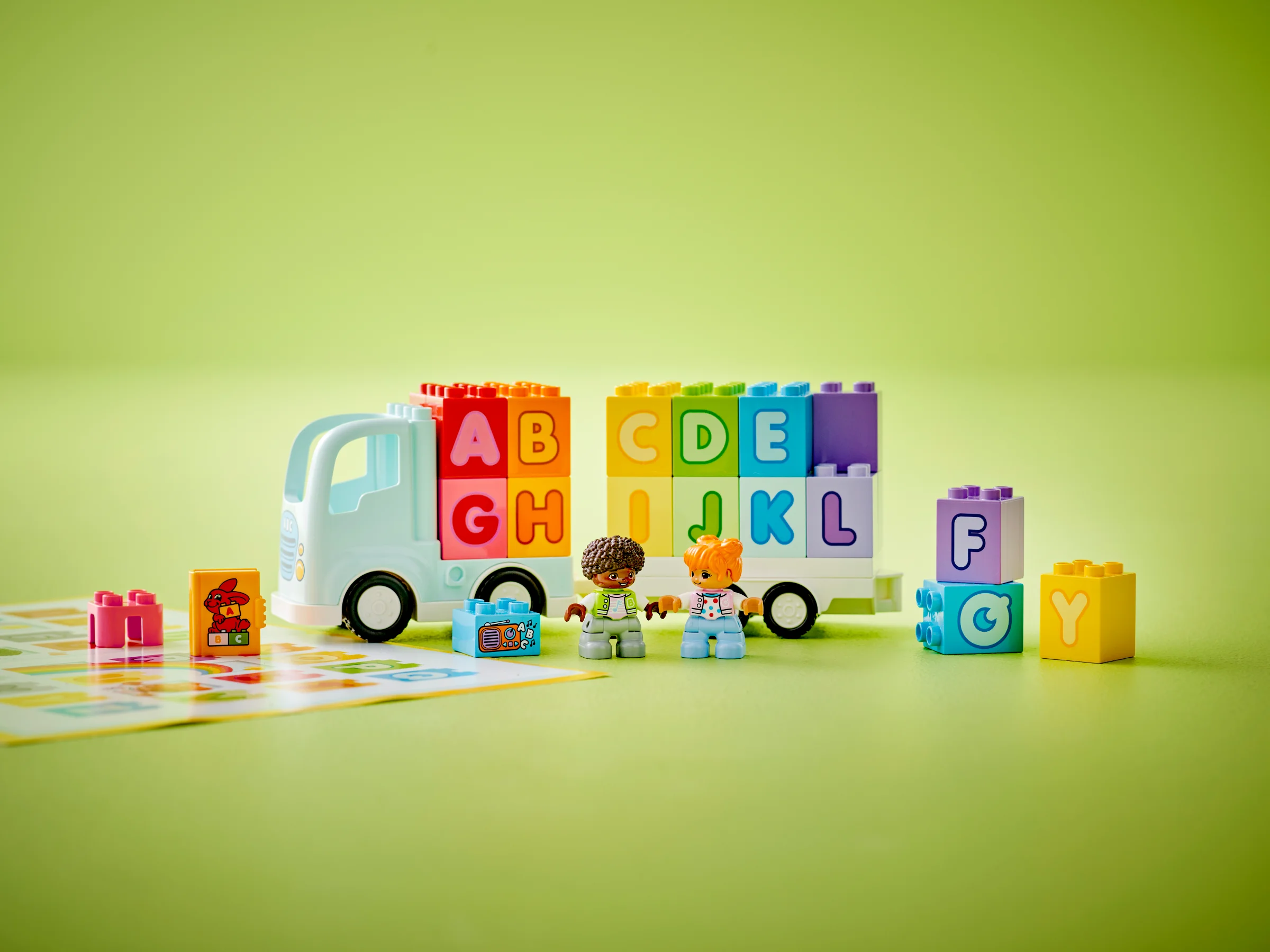 Camion cu litere Duplo colorate și două figurine, ideal pentru învățarea alfabetului.
