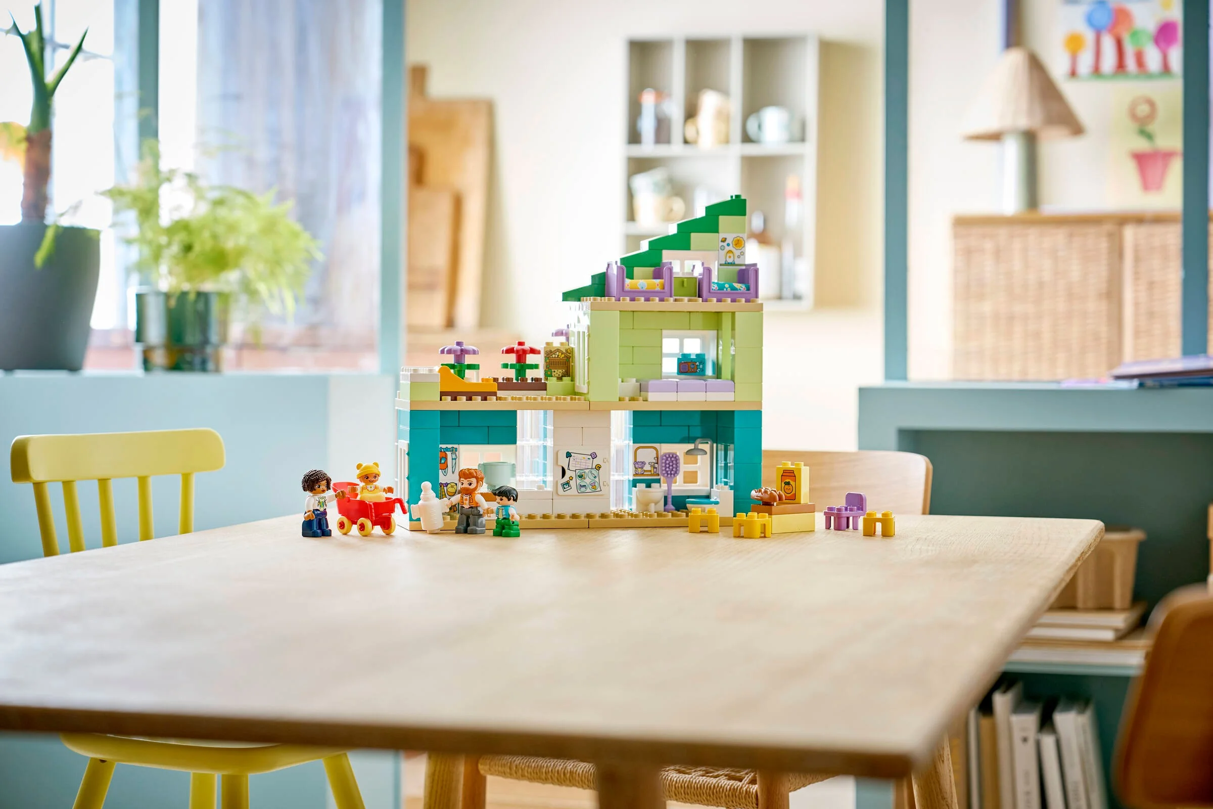 Imagine cu casa modernă Duplo 10470, cu figurinele familiei, pe o masă de lemn. Luminoasă și primitoare.
