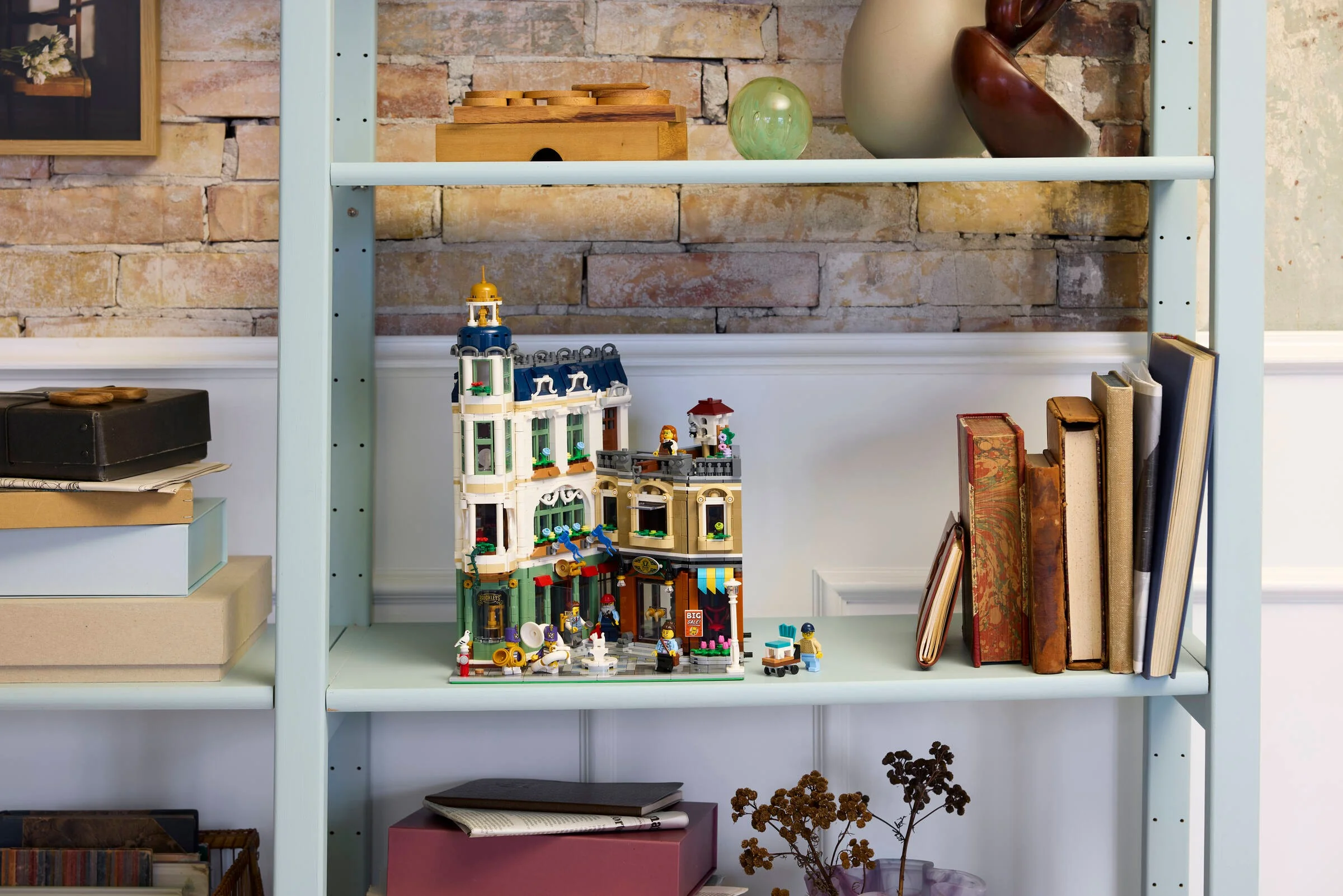 Setul LEGO 11371 Strada Comercială prezentat pe un raft. Include clădirea și minifigurine.