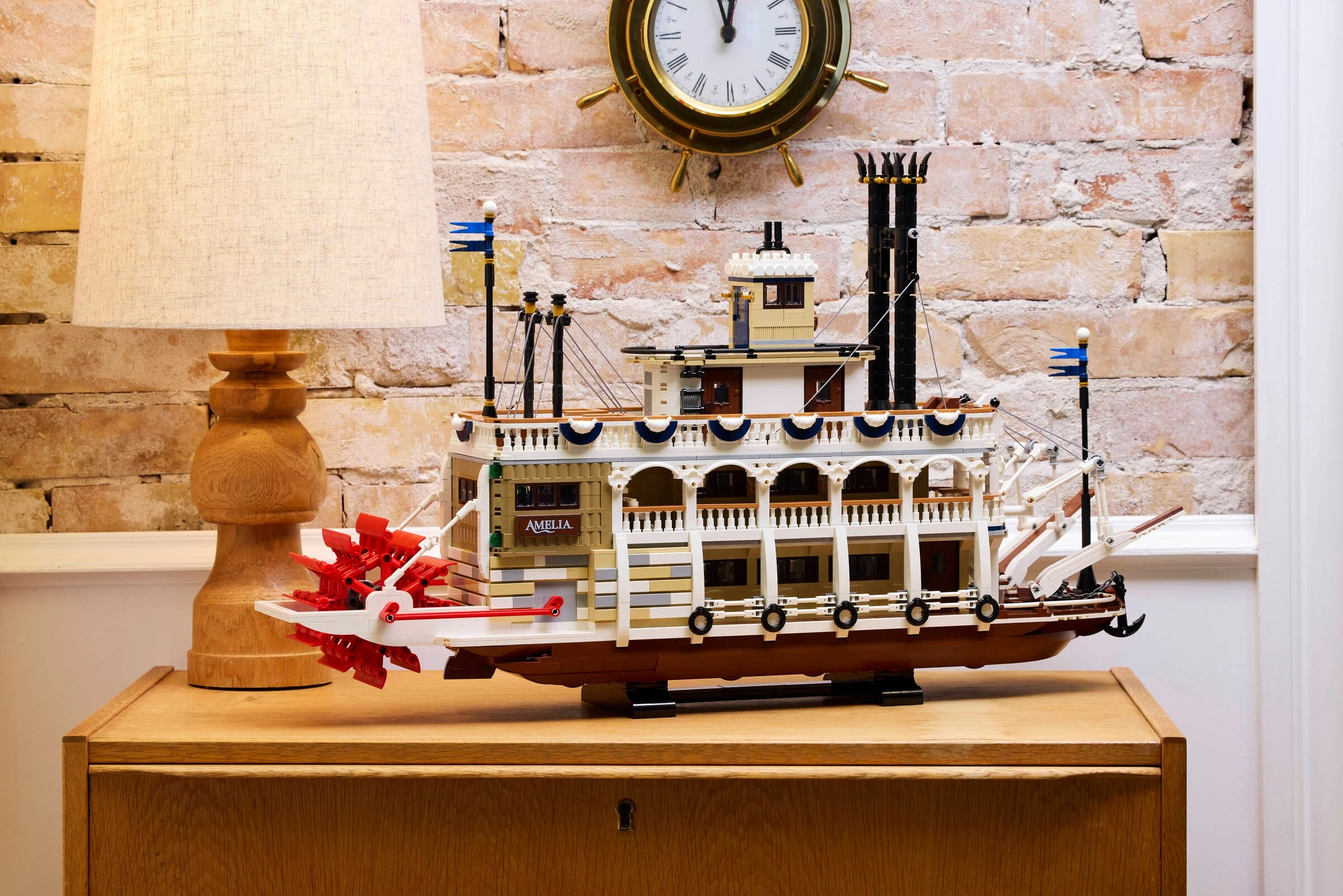 O imagine detaliată a vaporului cu aburi LEGO Ideas 21356, expus pe o comodă de lemn.