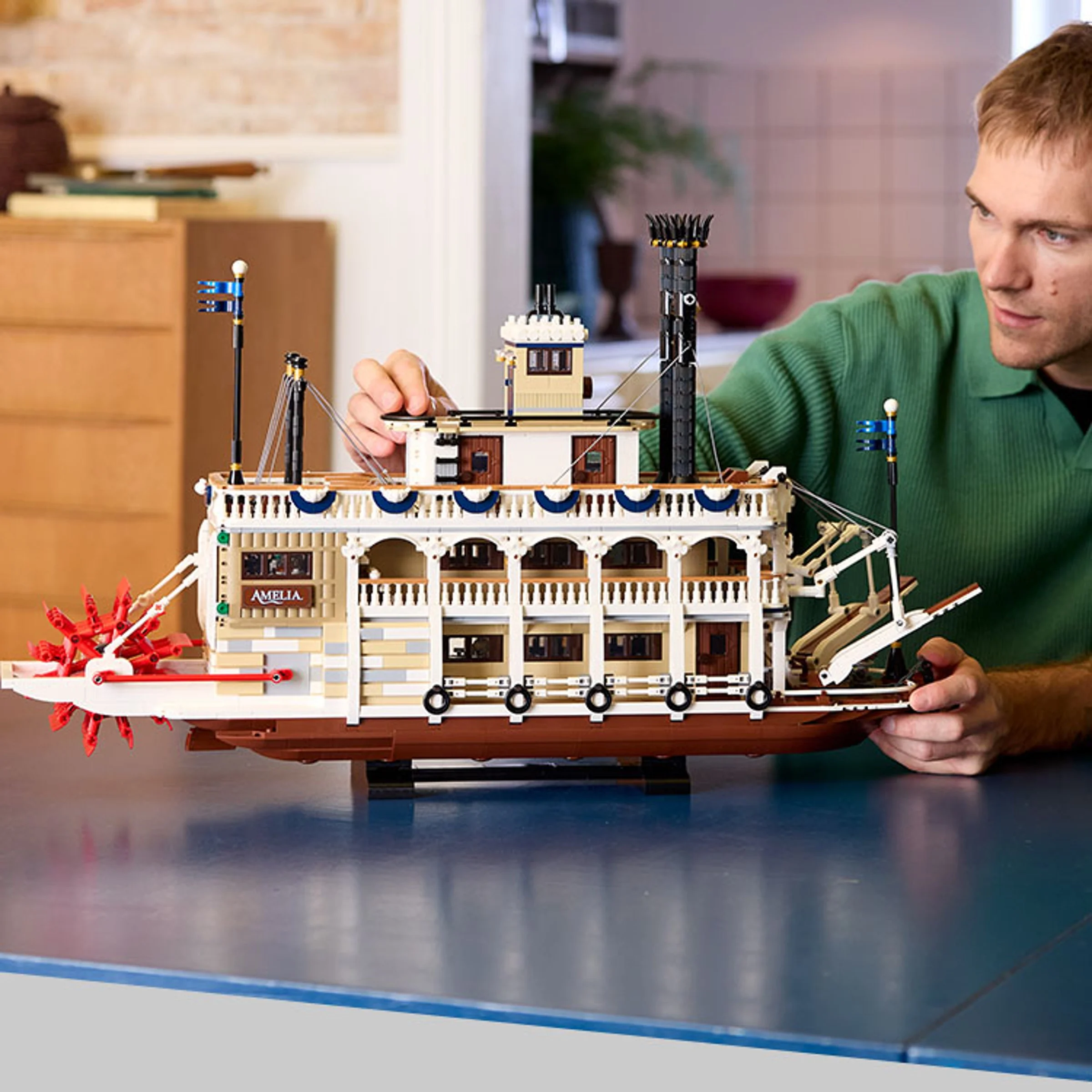 Modelul LEGO al vaporului fluvial, cu un bărbat adult inspectând detaliile. Construcție complexă.