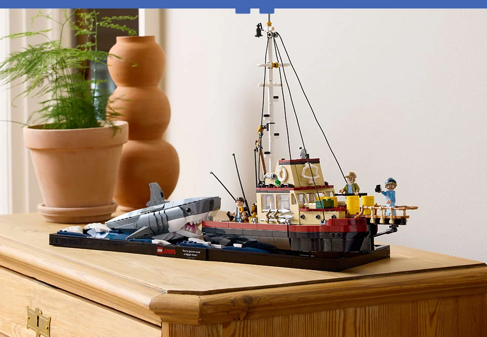 Imagine cu setul LEGO Jaws, ce prezintă barca și rechinul. Modelul e așezat pe o comodă.