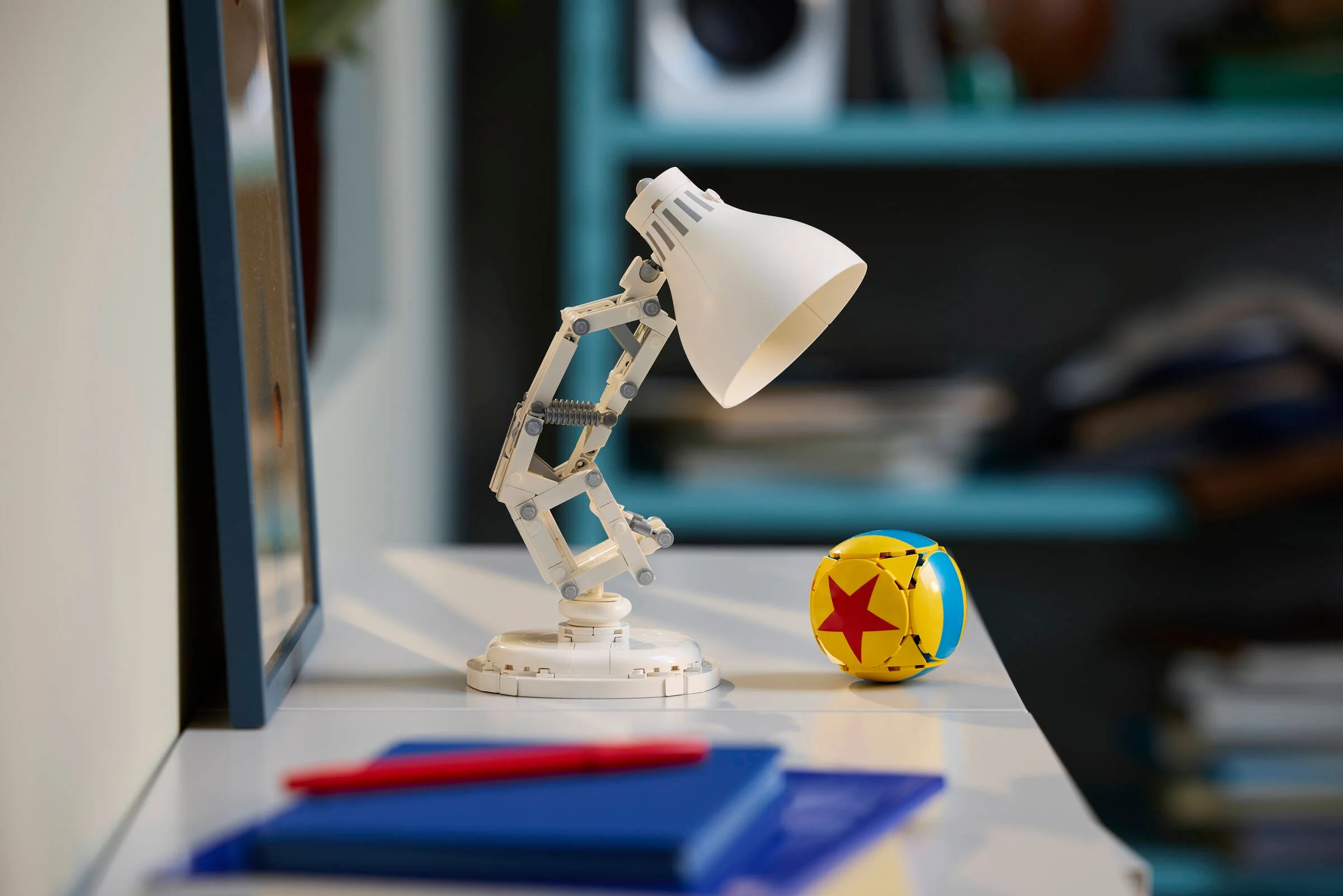 Model LEGO Luxo Jr. și mingea Pixar pe o masă. Design detaliat și recreere fidelă.