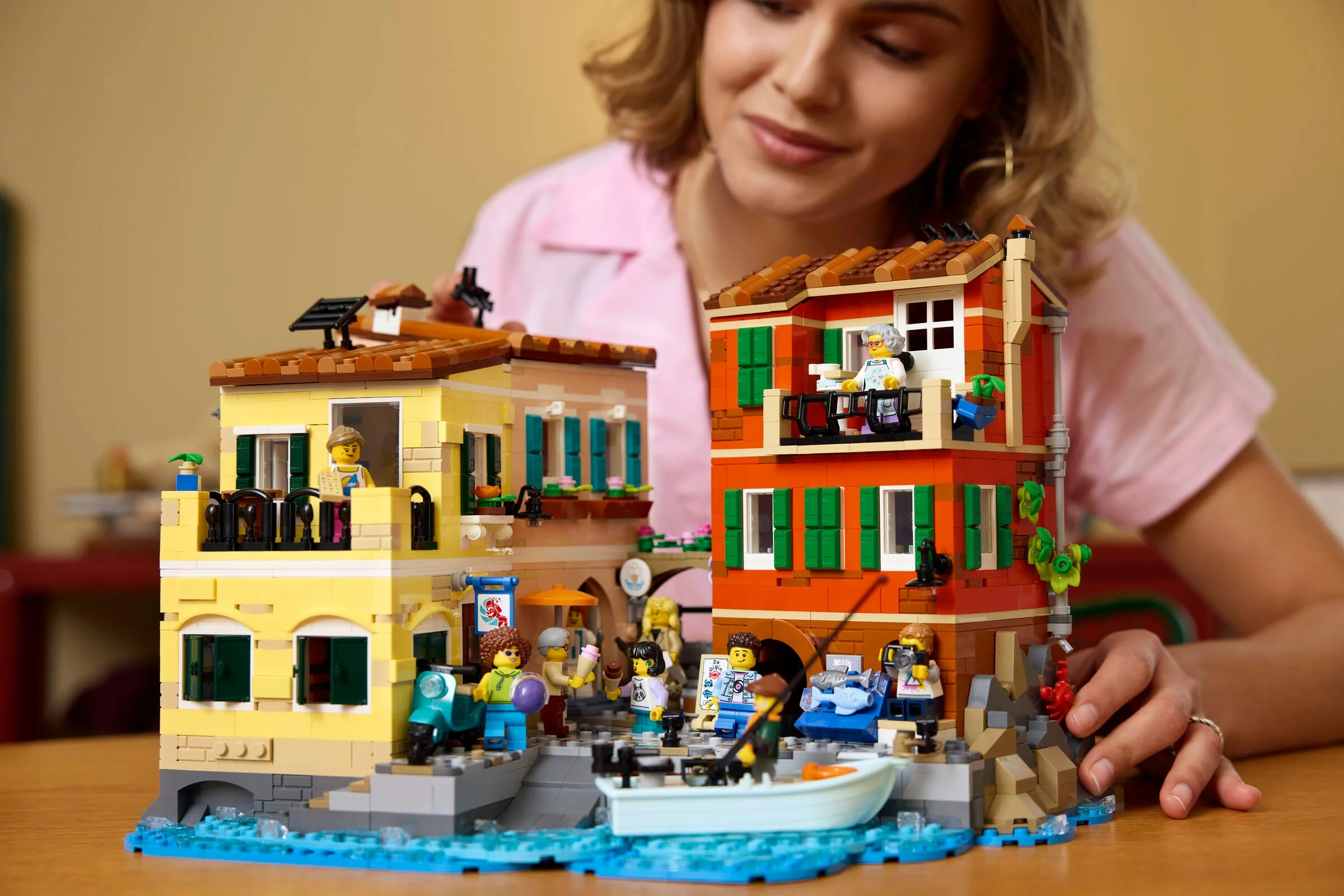 Imagine cu modelul LEGO Riviera Italiană 21359, cu clădiri colorate și minifigurine pe malul apei.
