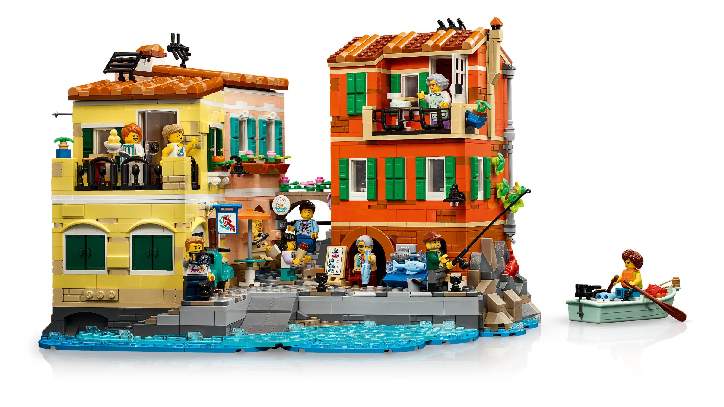 Setul LEGO Ideas 21359 Riviera Italiană. Case colorate, minifigurine și o barcă pe apă.