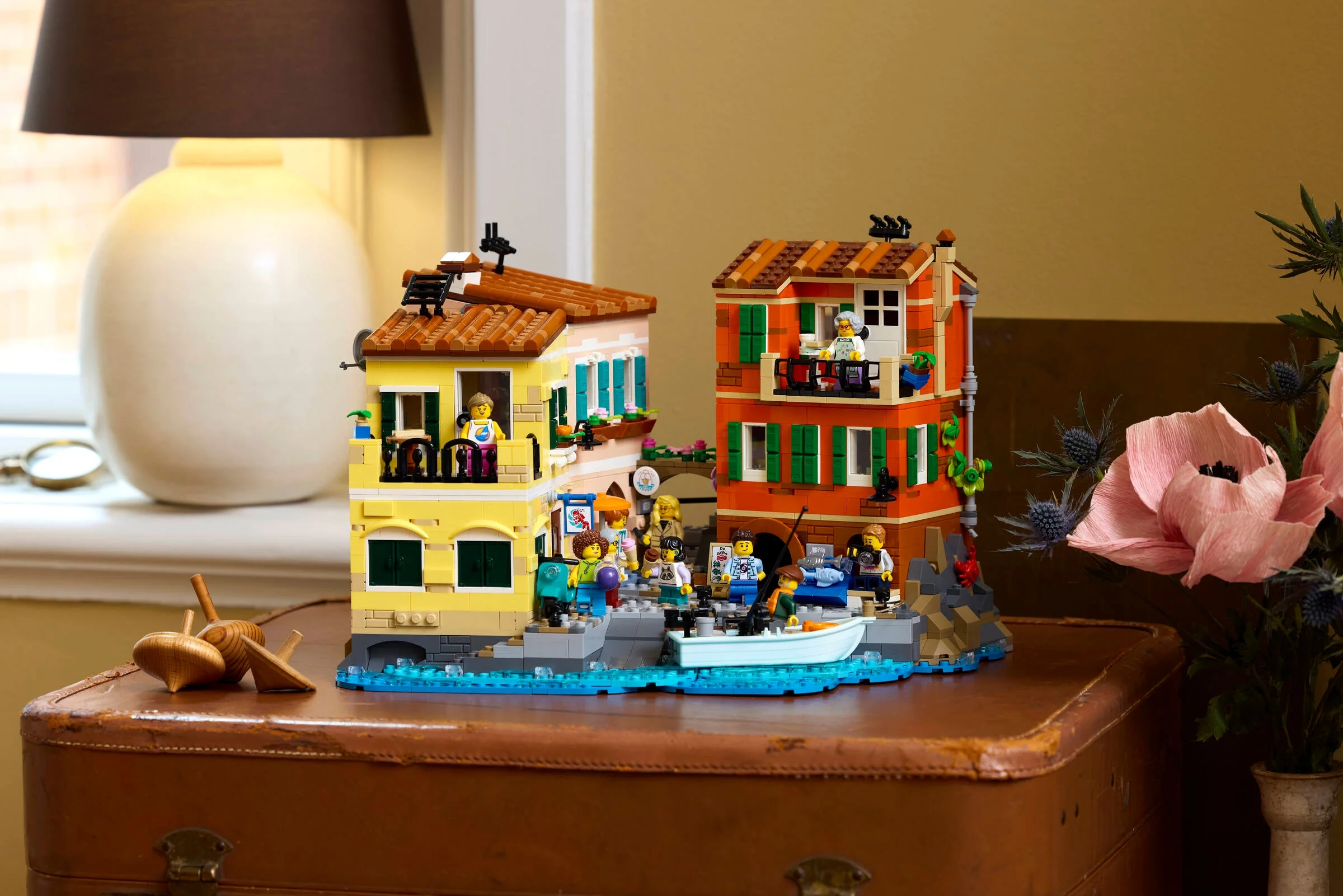 Imagine cu setul LEGO Ideas 21359 Riviera Italiană, viu colorat, pe o valiză veche.