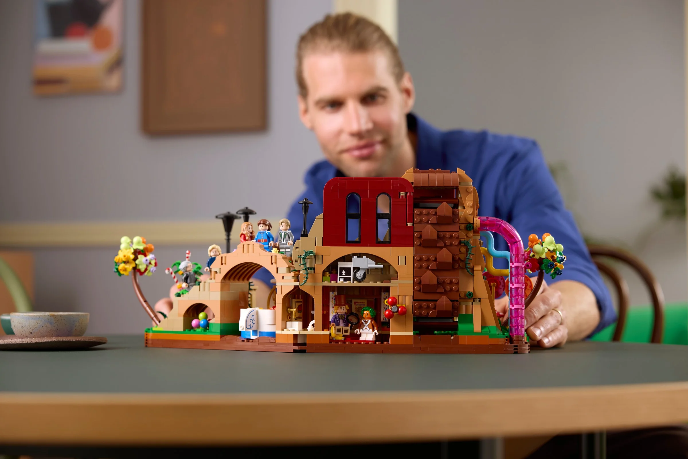 Modelul LEGO Willy Wonka & the Chocolate Factory expus pe o masă, cu o persoană în fundal.