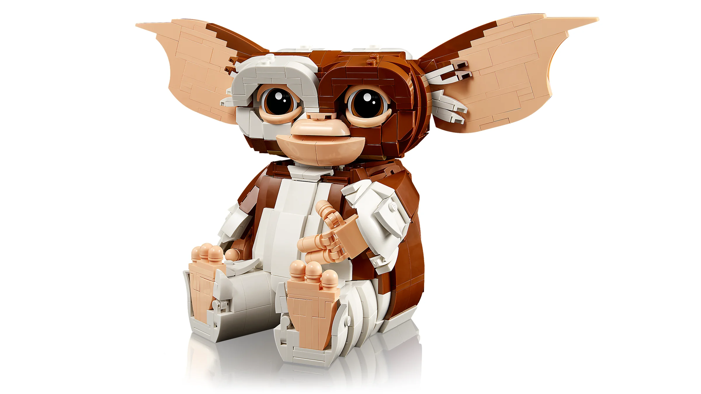 O imagine cu Gizmo construit din piese LEGO, așezat cu mâinile la gură, arătând drăguț.