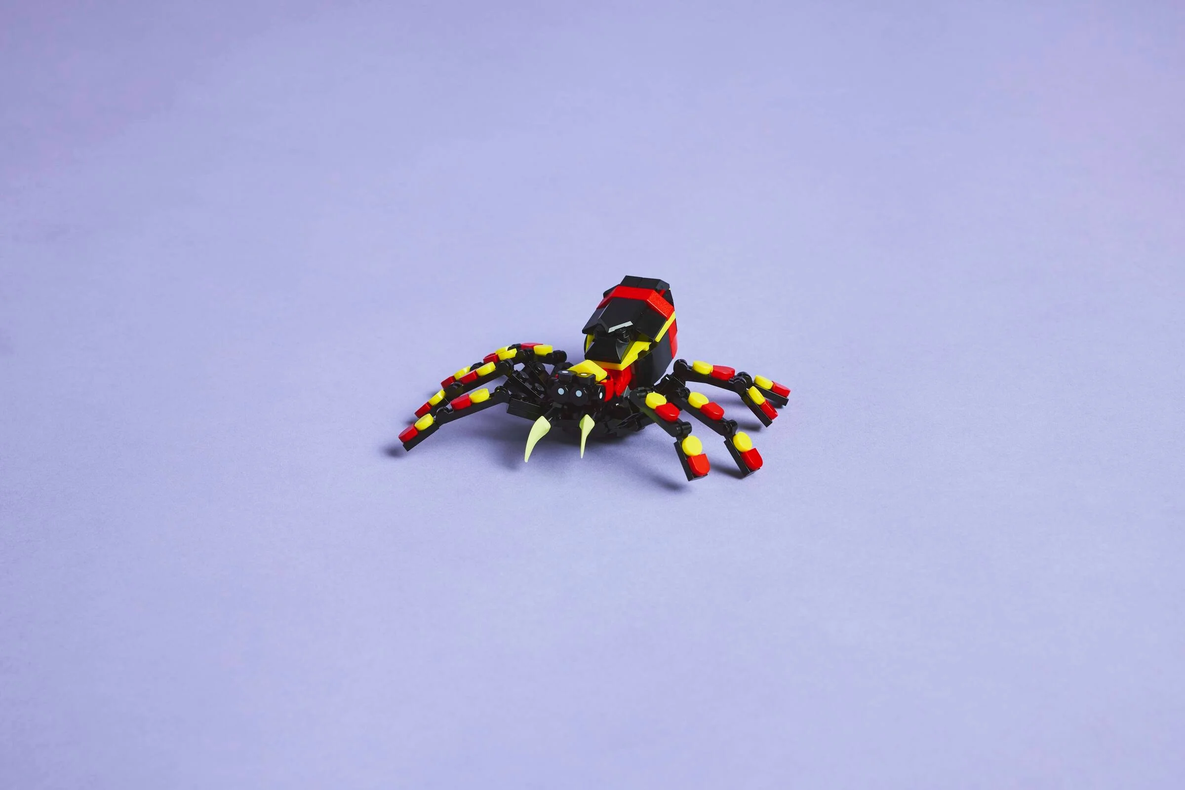 O imagine a păianjenului LEGO 31159, negru cu detalii roșii și galbene. Arată detaliile construcției.
