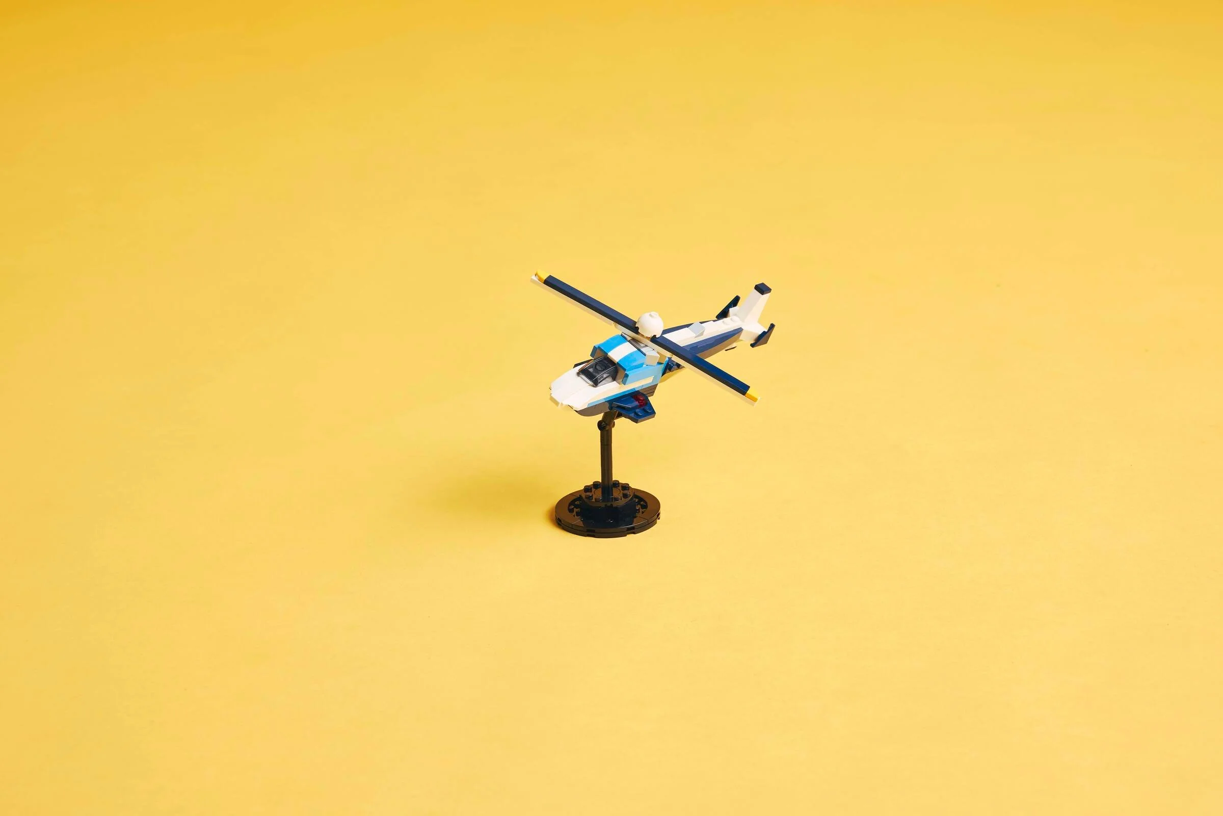 Avion de curse alb-albastru, stilizat, pe un suport negru. Un model simpatic.